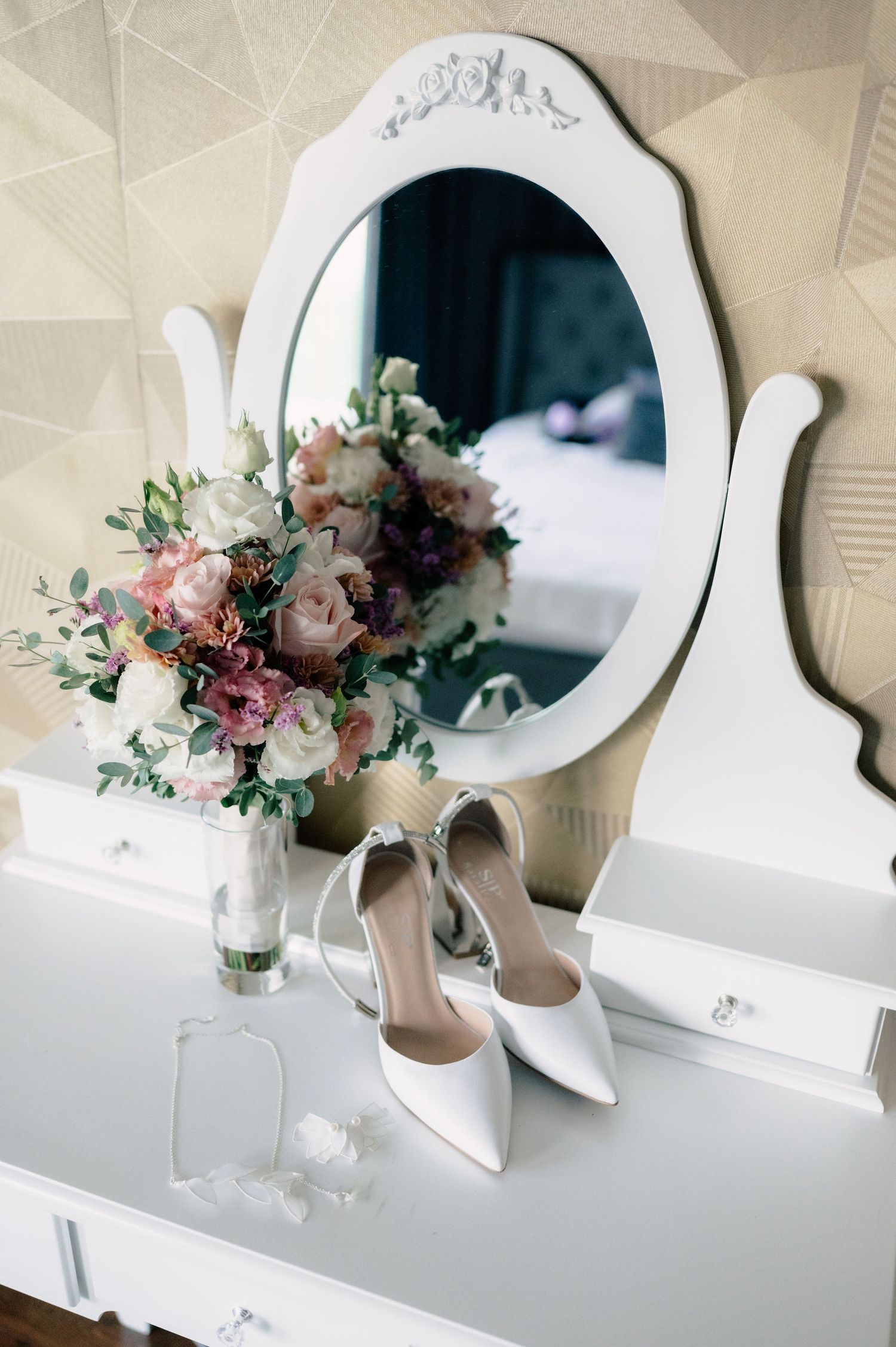 Beautiful floral arrangement with pink and white roses sits elegantly on white vanity table with ornate mirror.