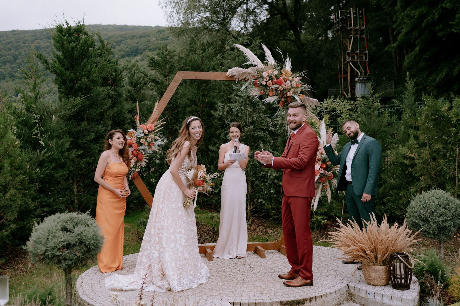 A group of people gather outdoors for a wedding ceremony in a lush garden setting.