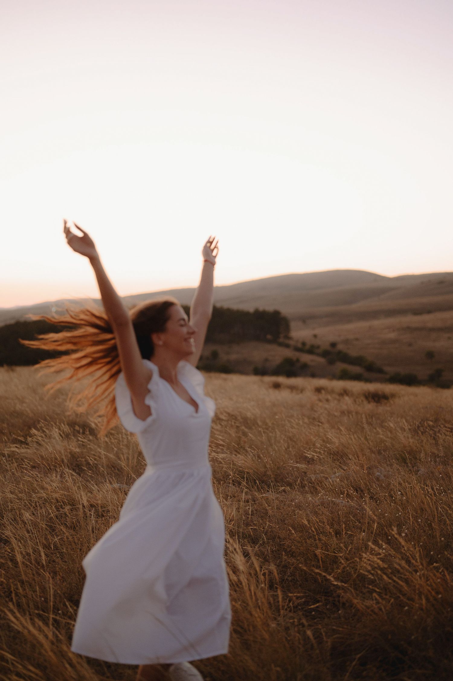 A figure in a flowing white dress dances gracefully through a golden field at sunset, creating a series of dynamic movements.