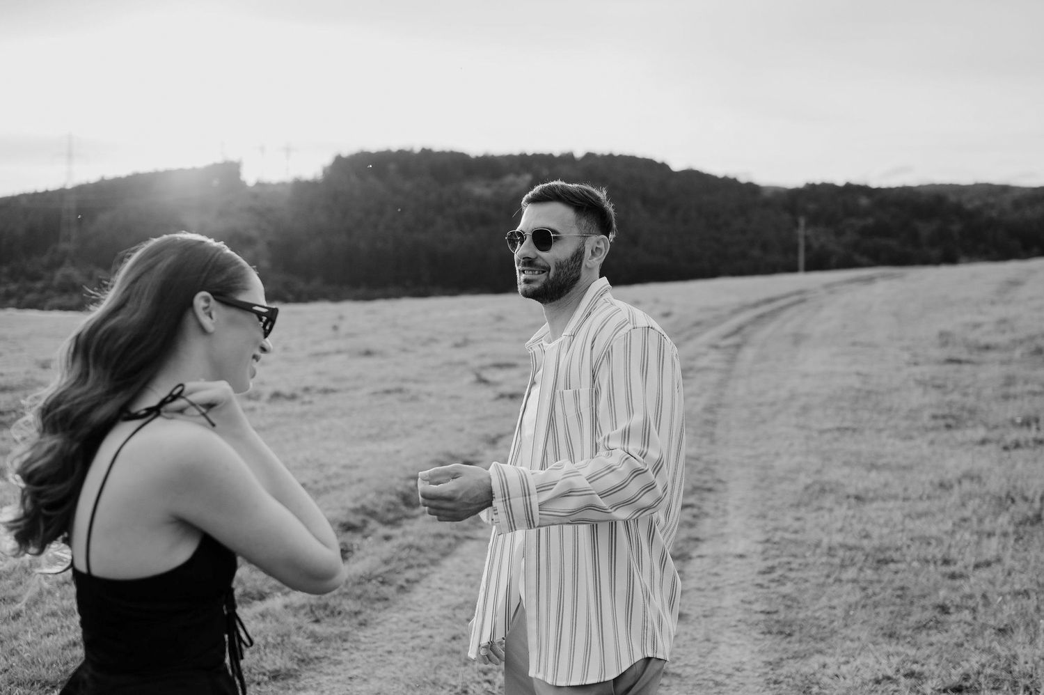 A couple shares a romantic moment in a field during a black and white photo session.