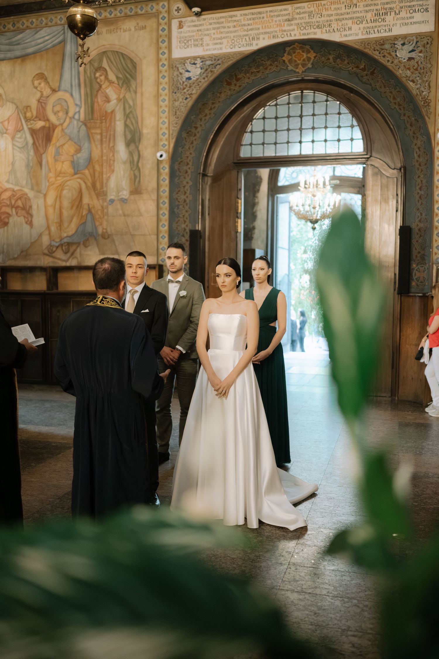 Elegant wedding ceremony in an ornate historic hall with frescoed walls and arched doorways.