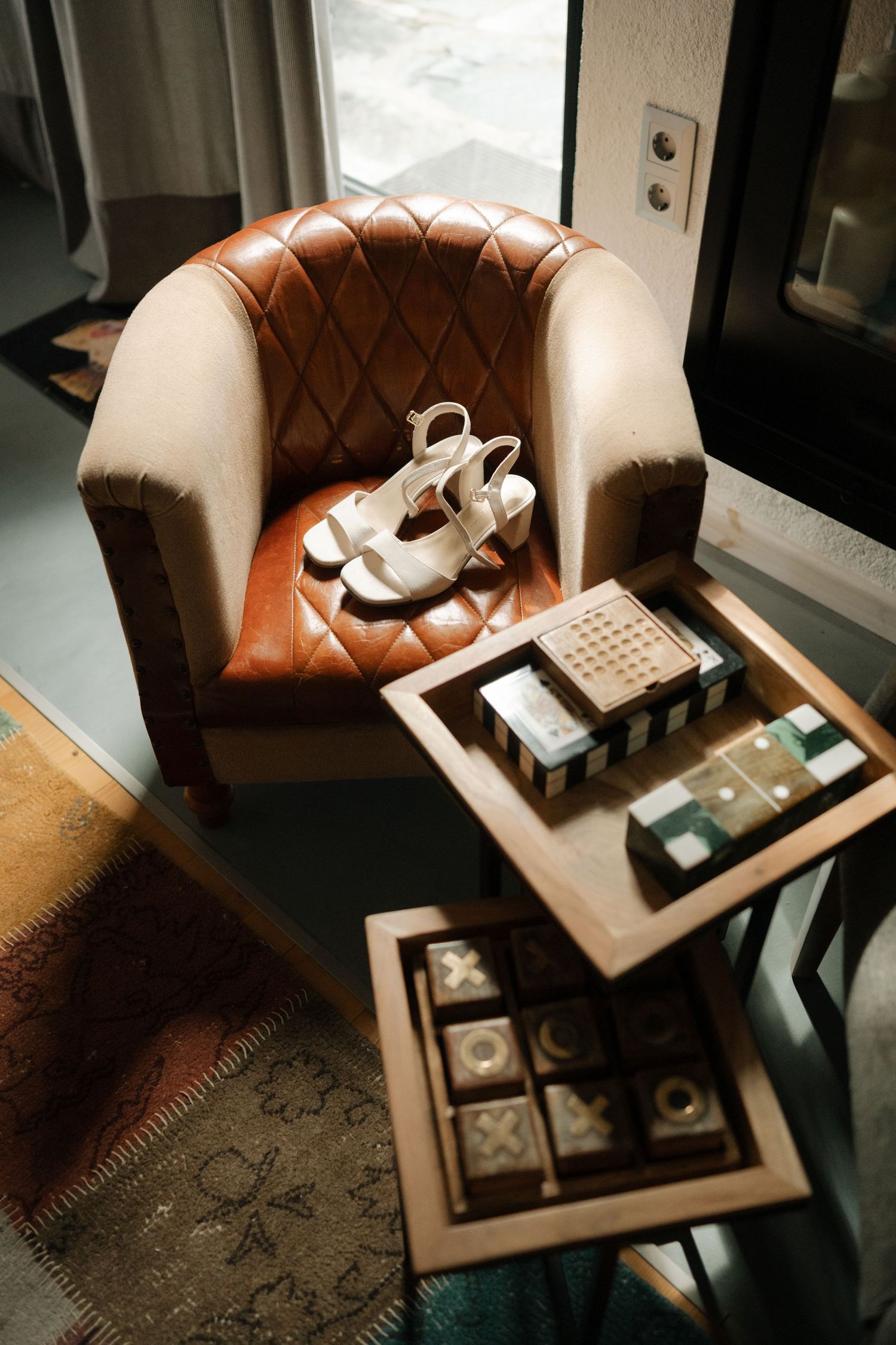 Leather armchair with vintage decor and serving tray displaying elegant tea service and accessories in moody lighting.