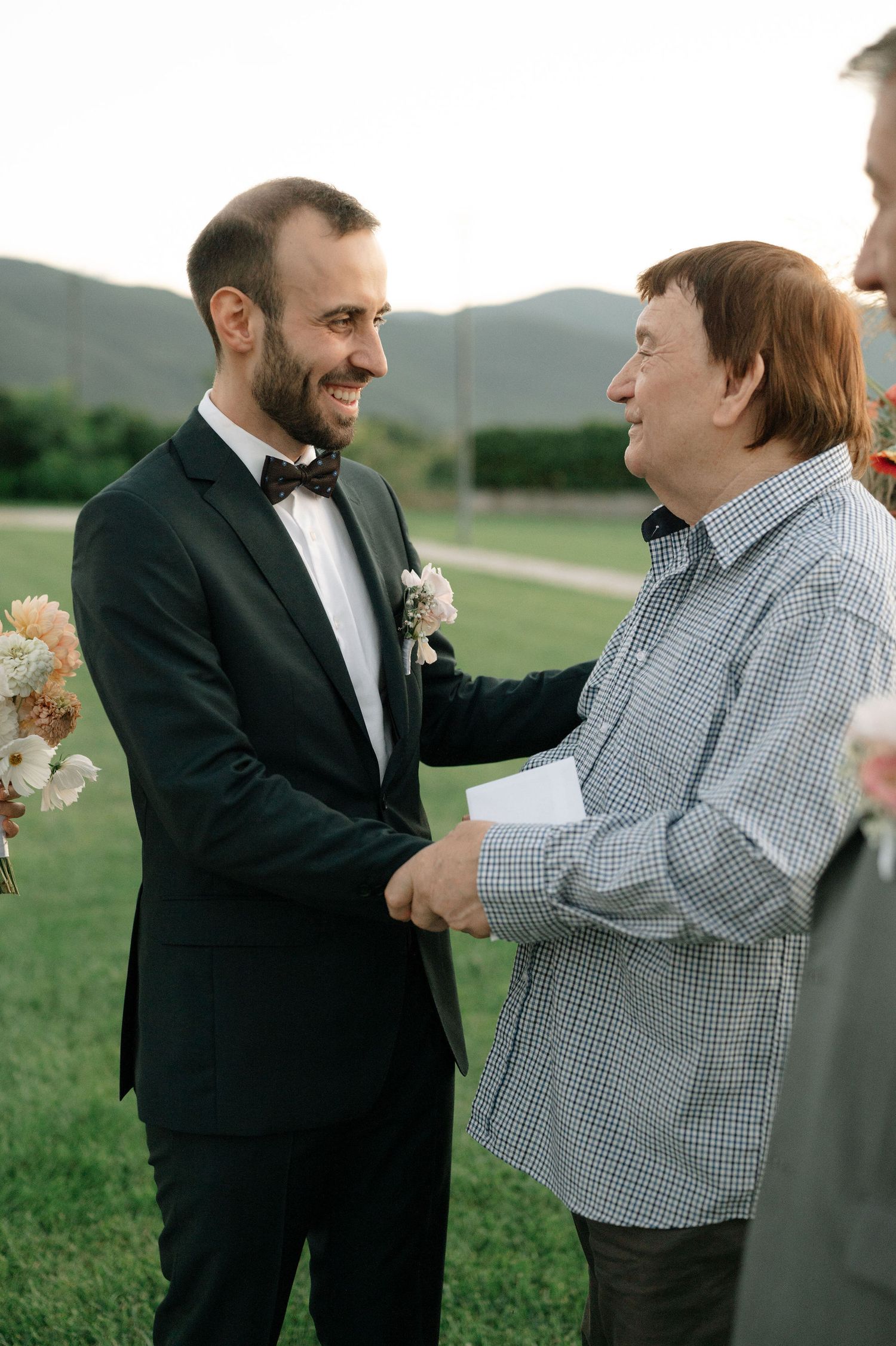 Two people share an emotional moment during an outdoor wedding ceremony with mountains in the background.