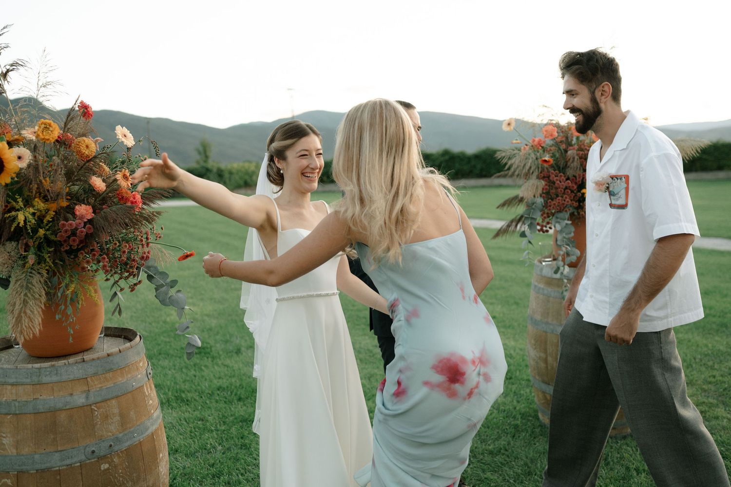 A couple dances playfully in a scenic outdoor setting with rolling green hills and golden sunlight.