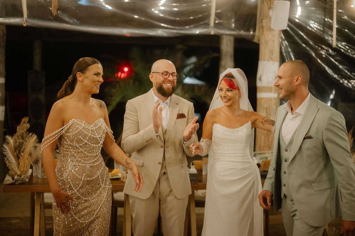 Wedding party laughing and dancing together during a festive celebration at an indoor venue.