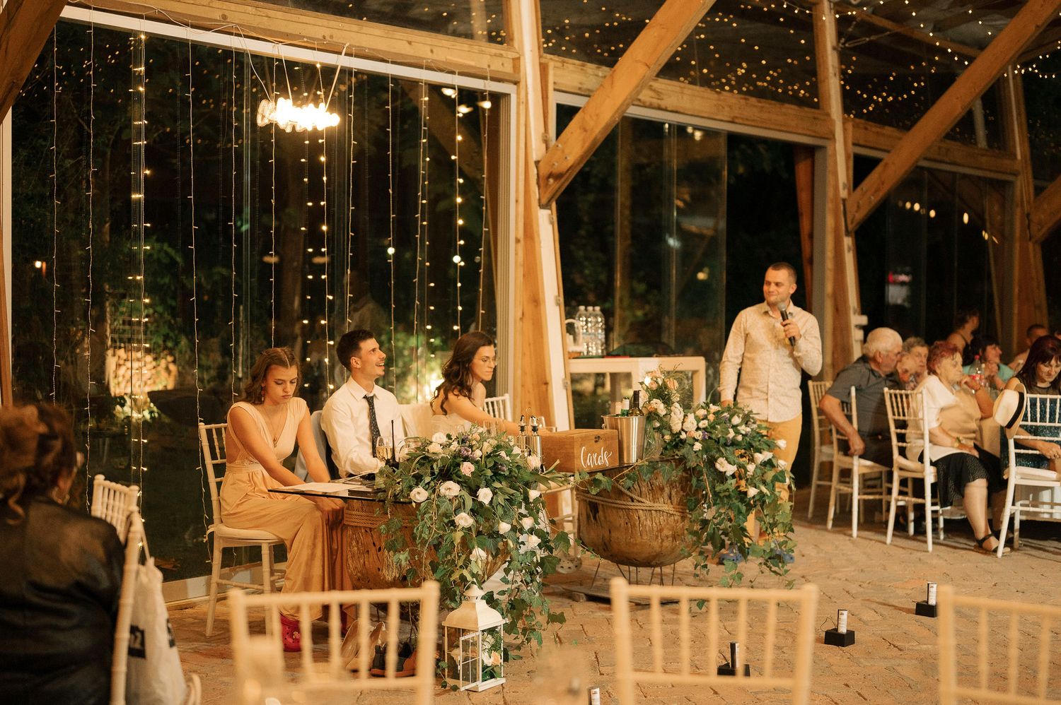 Rustic wooden barn wedding venue with twinkling lights and elegant table settings for an evening reception.