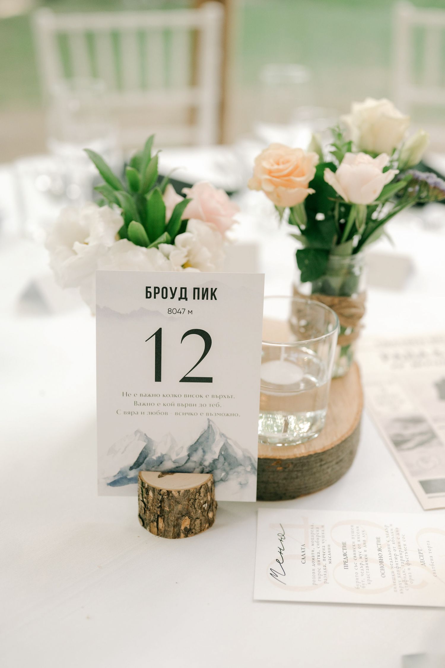 Elegant wedding table settings with mountain-themed place cards and small potted succulents in rustic holders.