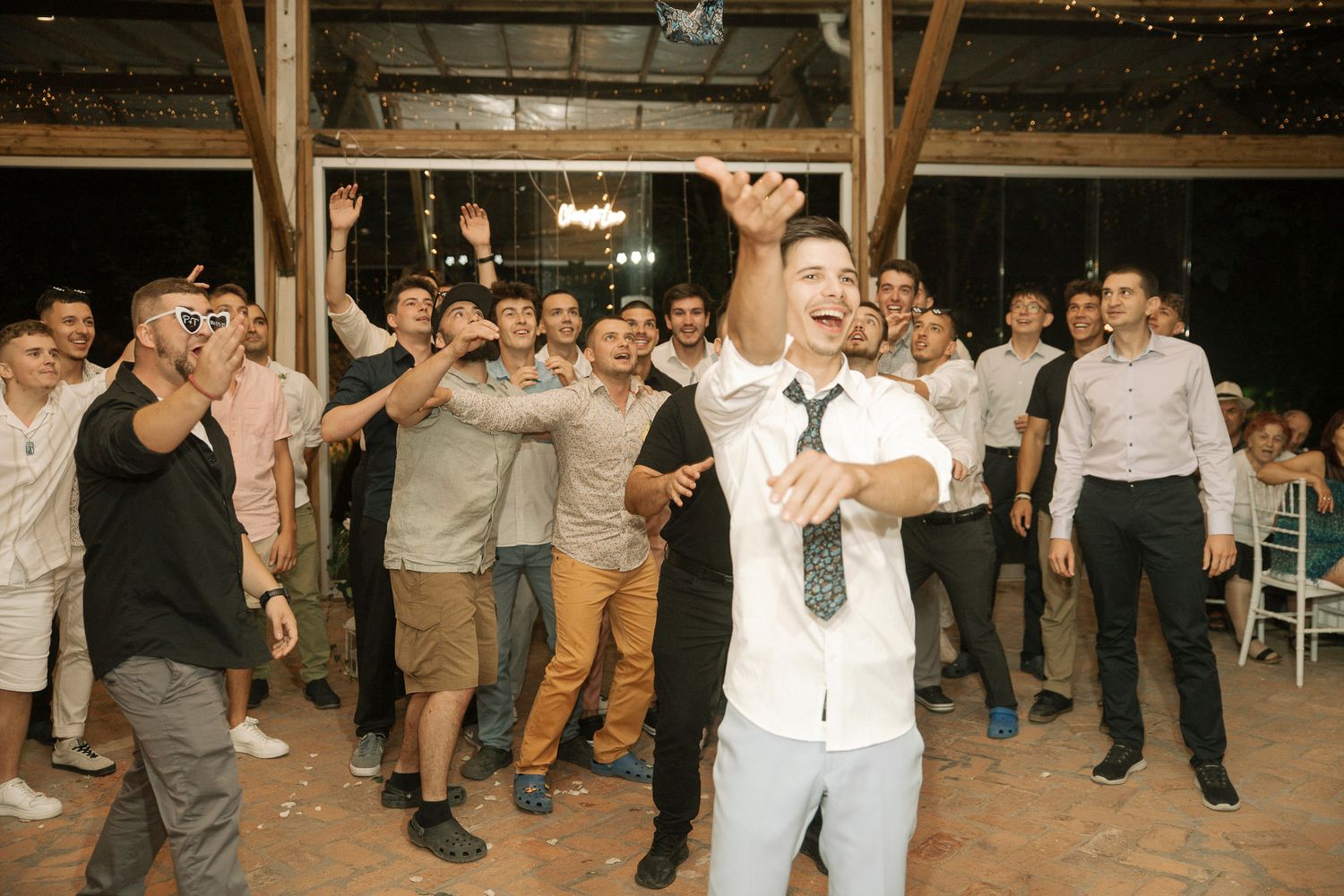 Guests enjoying line dancing at a festive outdoor wedding reception under string lights.