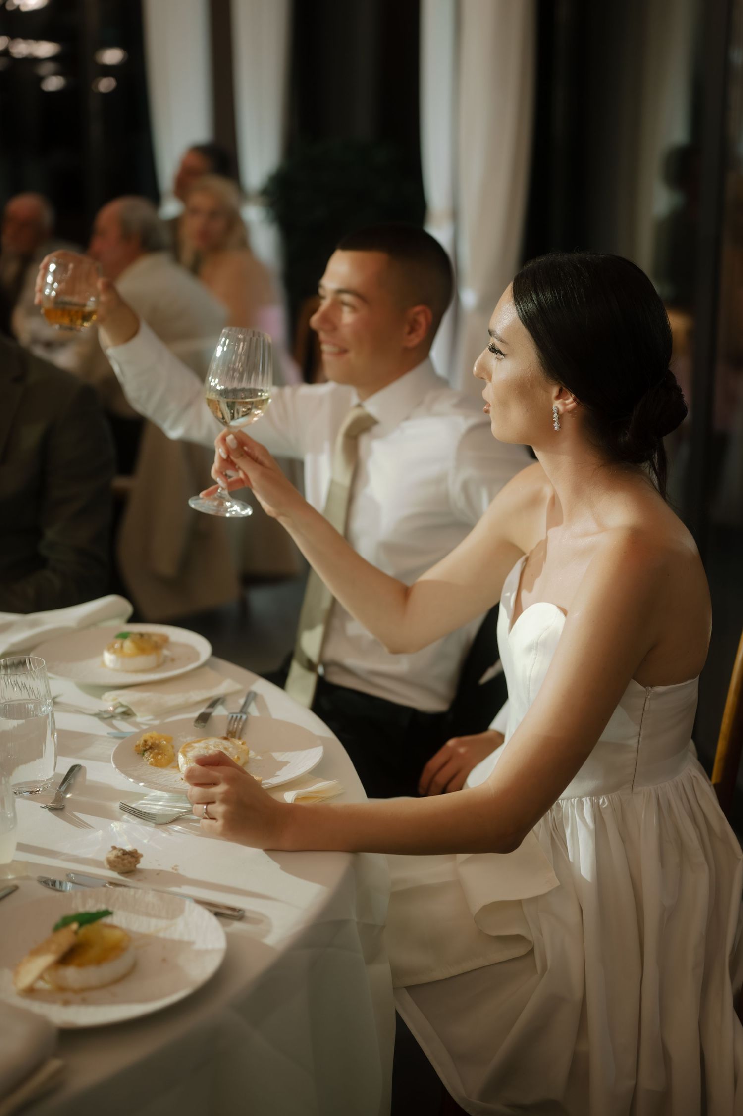 A series of elegant dining scenes at a formal event showing guests in white attire raising wine glasses at a banquet table.