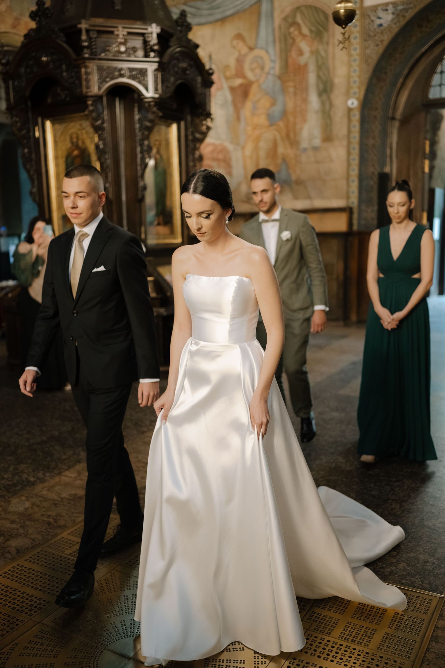 Elegant couple walking through ornate hallway during wedding ceremony in historic venue with decorative walls.