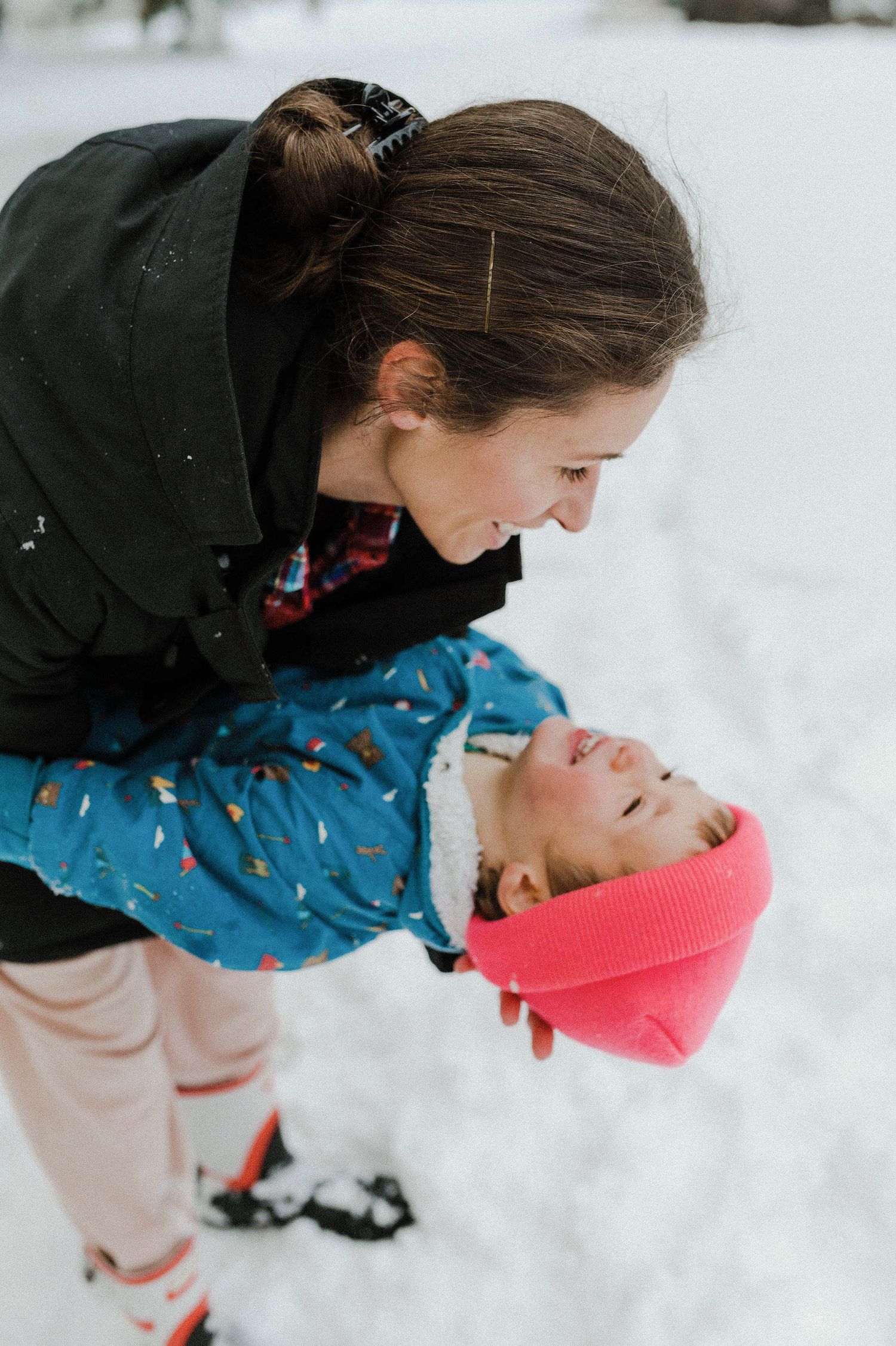 A sequence of photos showing a person in a black jacket leaning down to kiss someone in a pink hat in the snow.