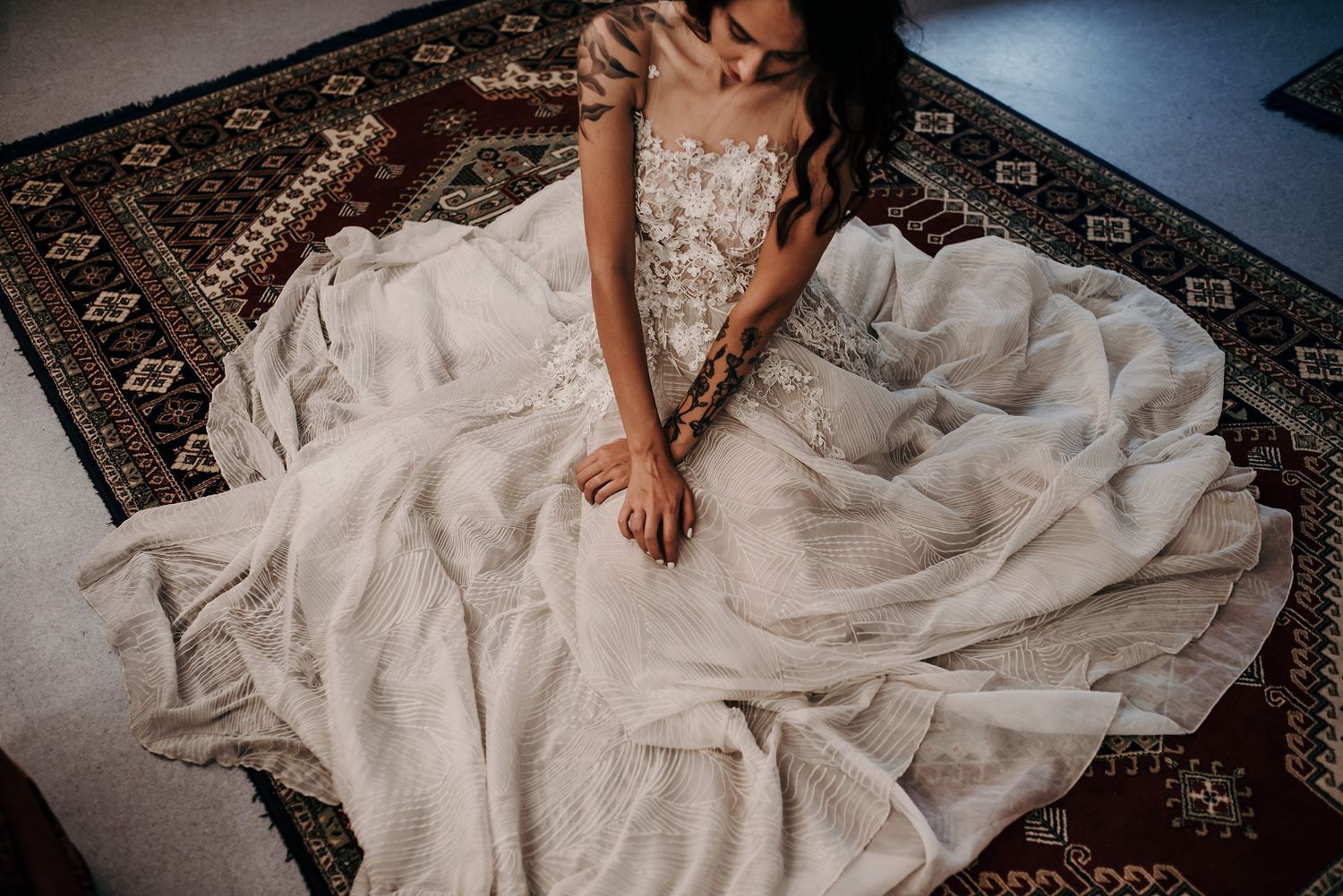 Wedding dress with flowing train spread elegantly across patterned carpet.