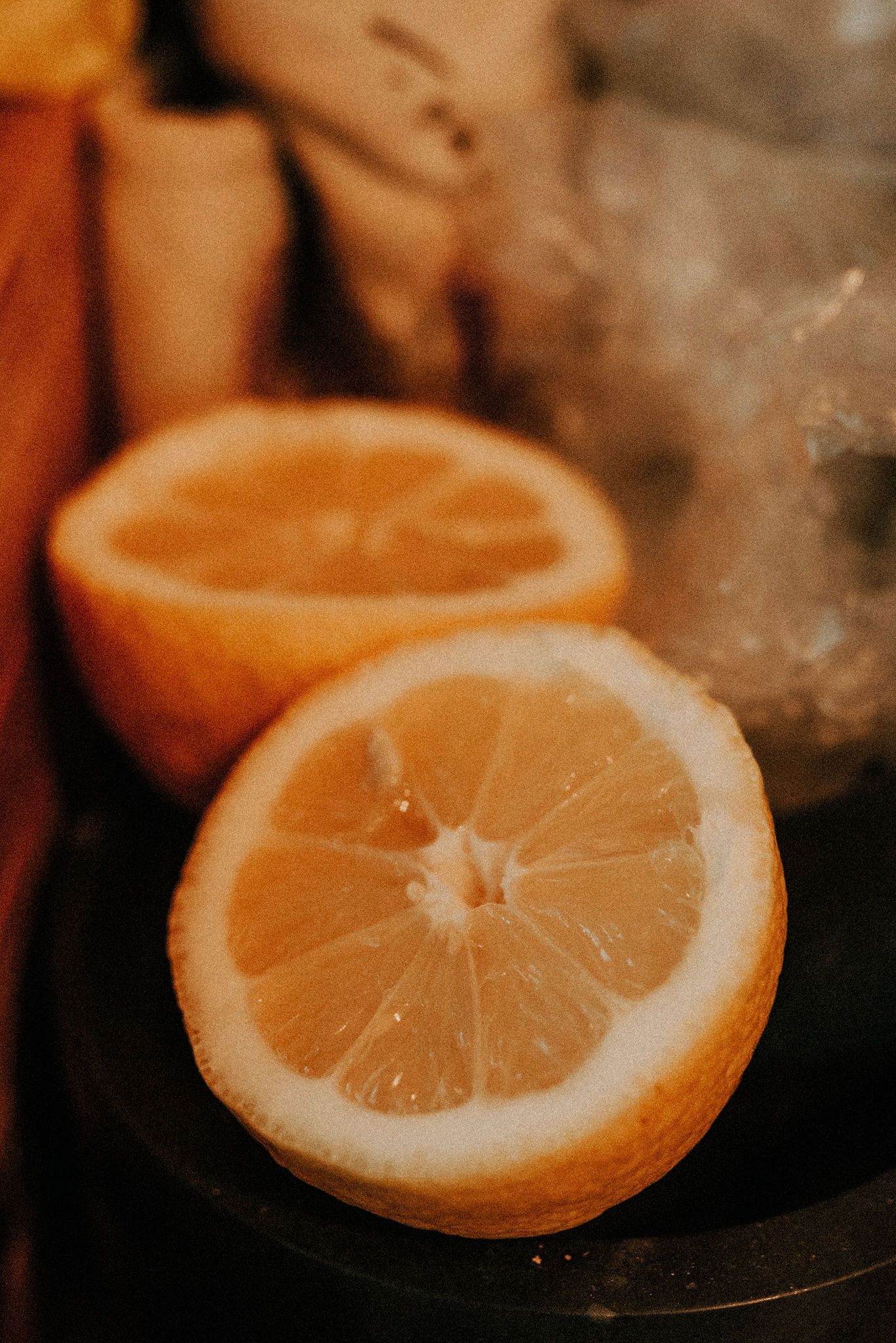 Close-up macro shot of fresh cut orange halves with steam in warm moody lighting.