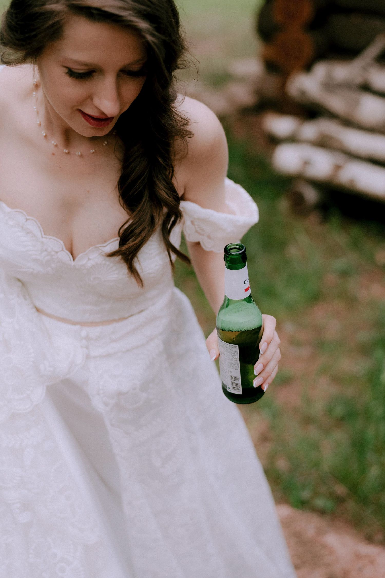 A bride in a white lace dress holds a bottle during a wedding celebration.