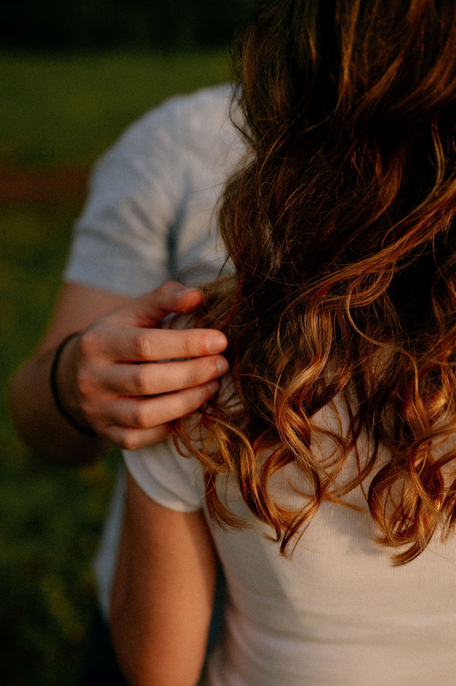 Close-up shot of wavy brown hair catching golden sunlight outdoors.