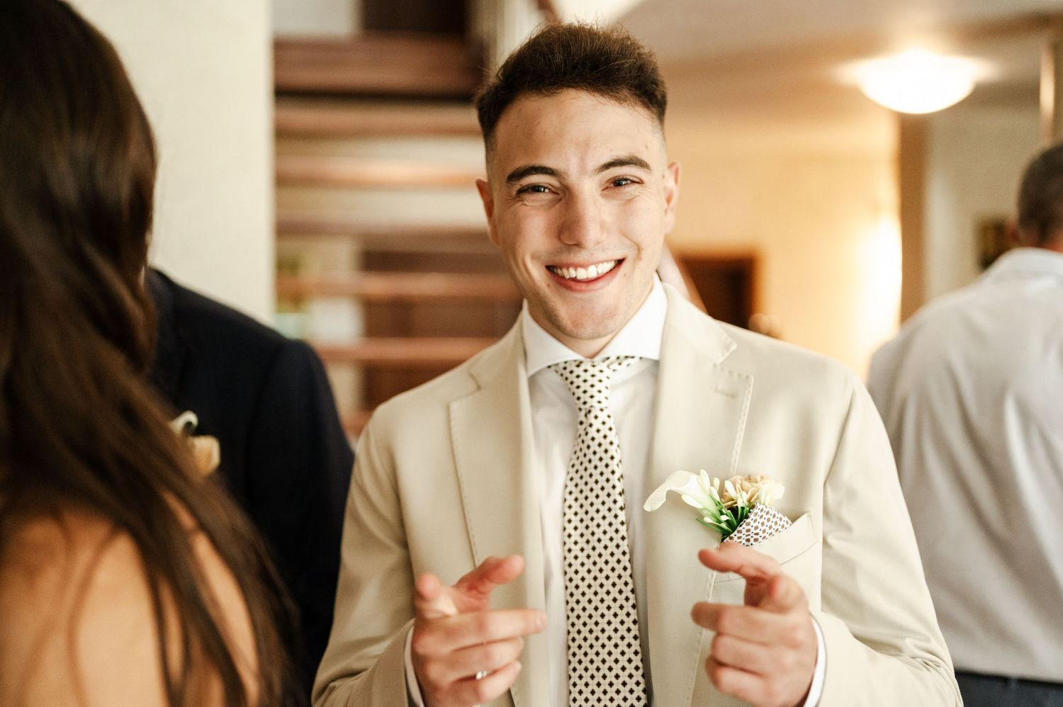 A person in white formal attire smiles during a celebration.