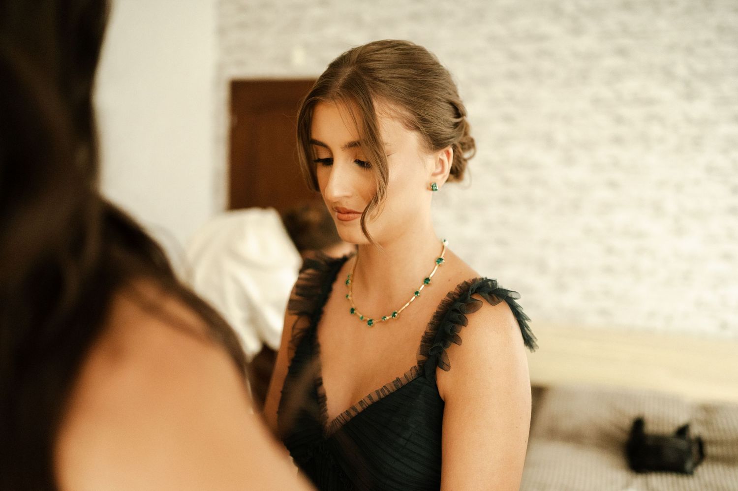 Elegant bridesmaid in black dress with feather detail at wedding preparation.