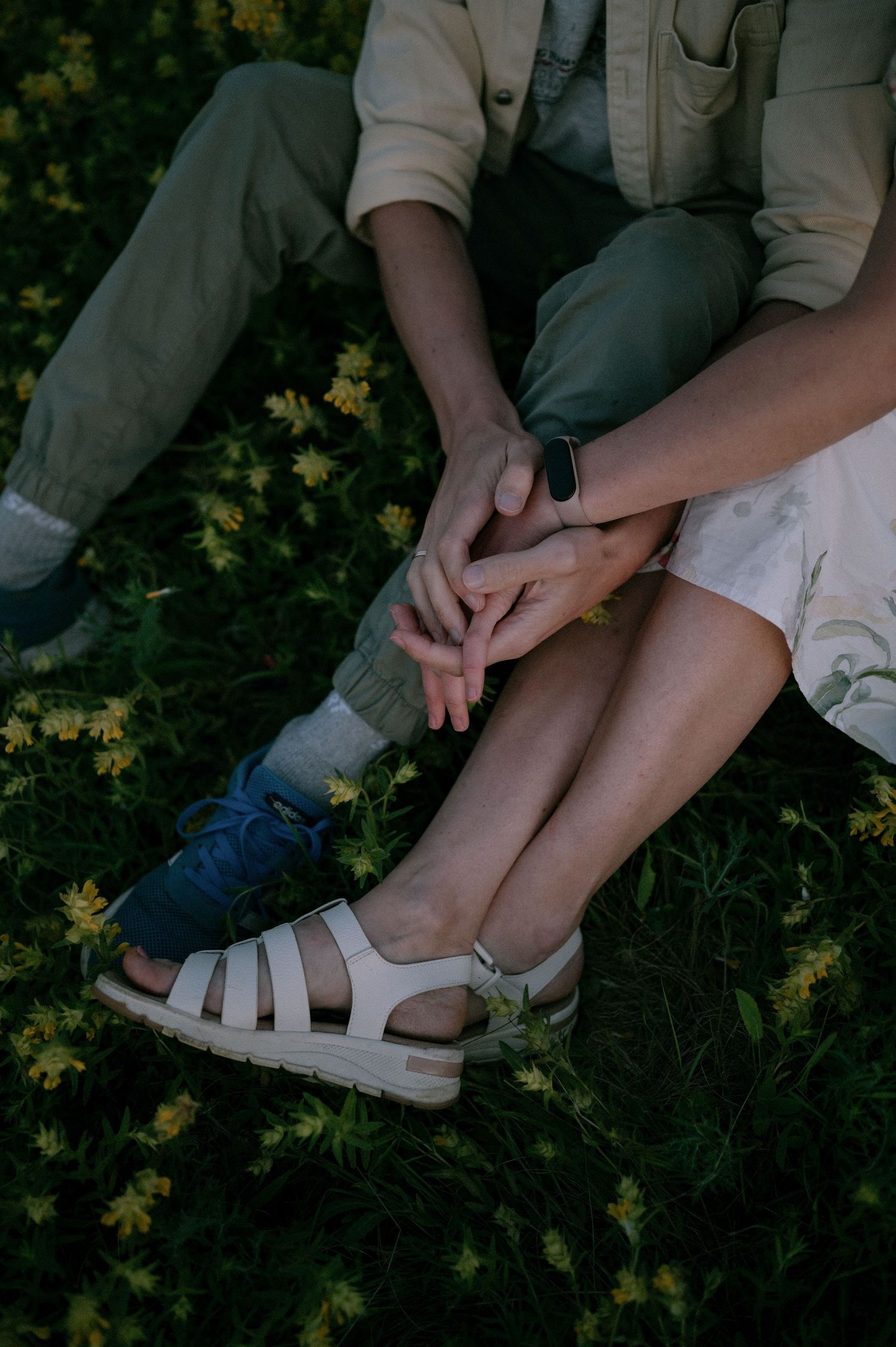 Close-up details of feet and sandals among yellow wildflowers in a meadow.