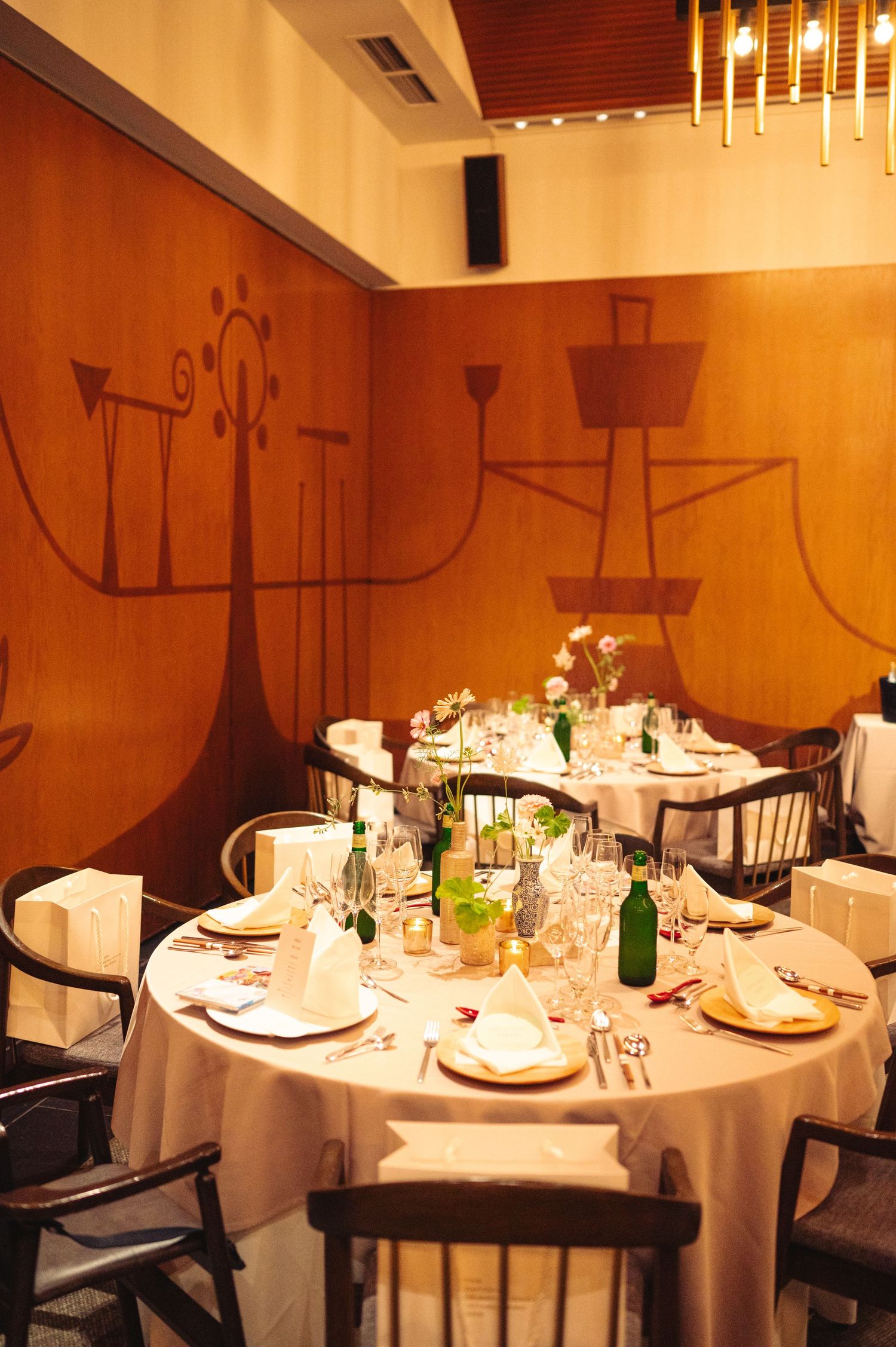 Intimate dining room with round tables and modern wall art in warm amber tones.