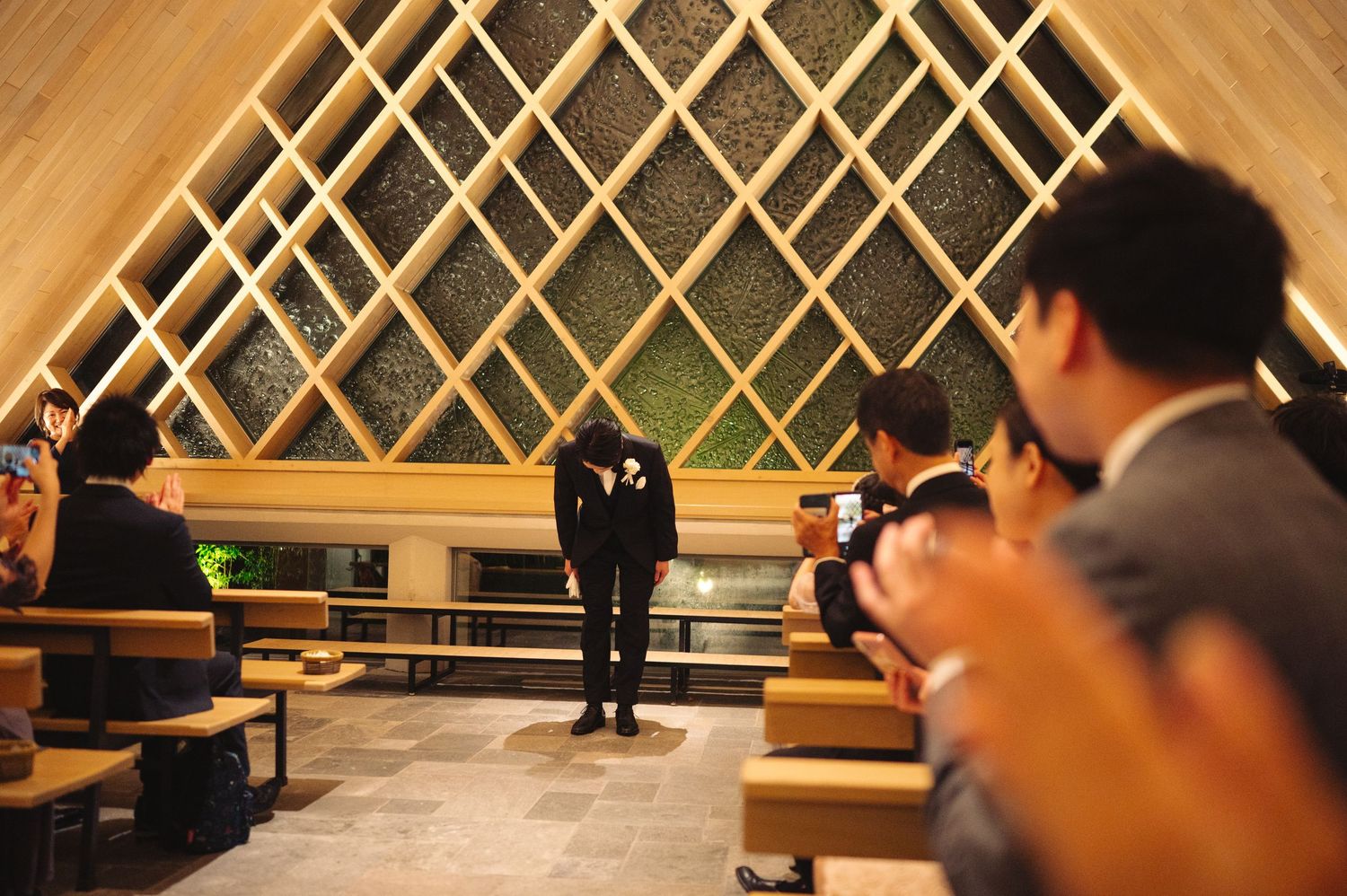 Modern venue interior with diagonal wooden lattice wall design and seated guests.
