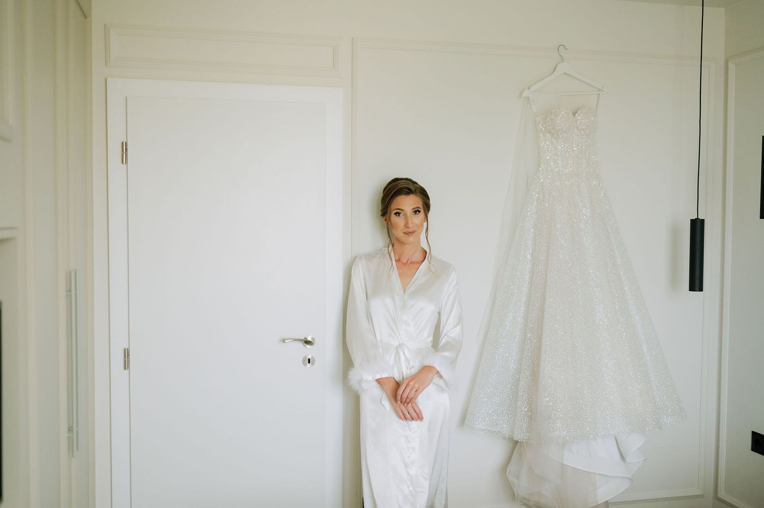 A wedding dress being fitted in a bright white room with natural lighting.
