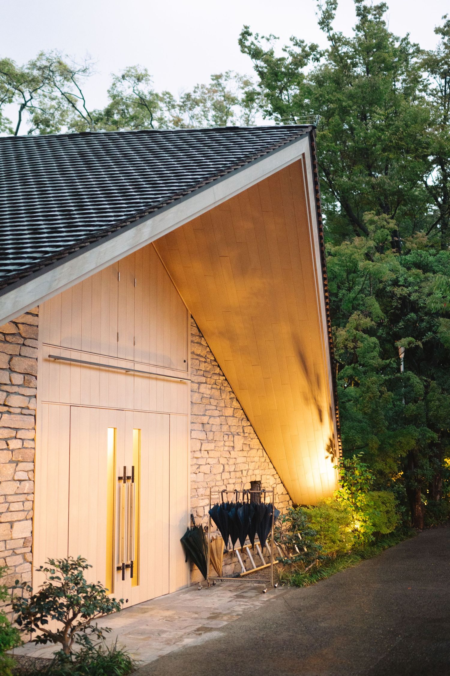 Modern white stone building with angled roof illuminated by warm exterior lighting at night.