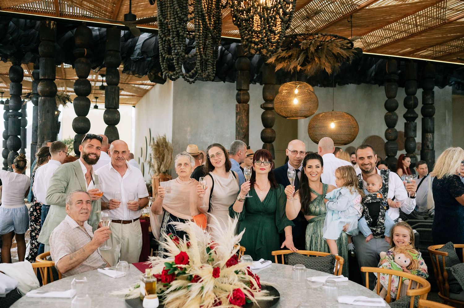 Large group of celebration guests gathered around decorated tables for a group photo.