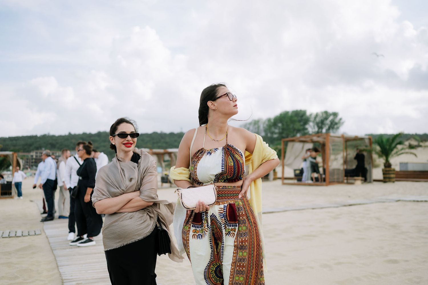 Guests enjoying conversation at an outdoor beach venue with decorative structures.