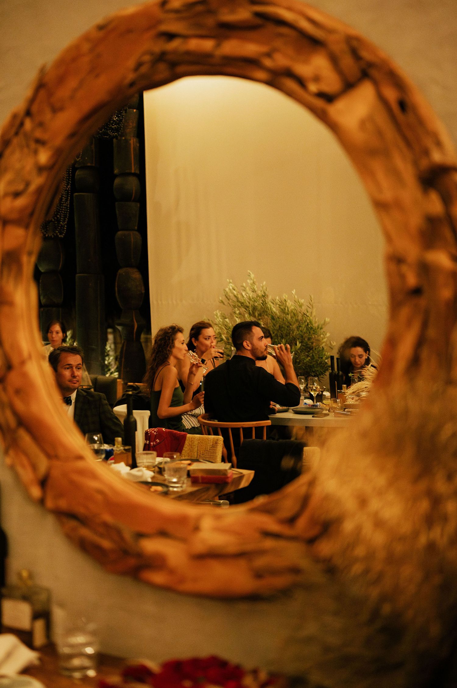 View through a rustic wooden mirror frame of an indoor dining setup.