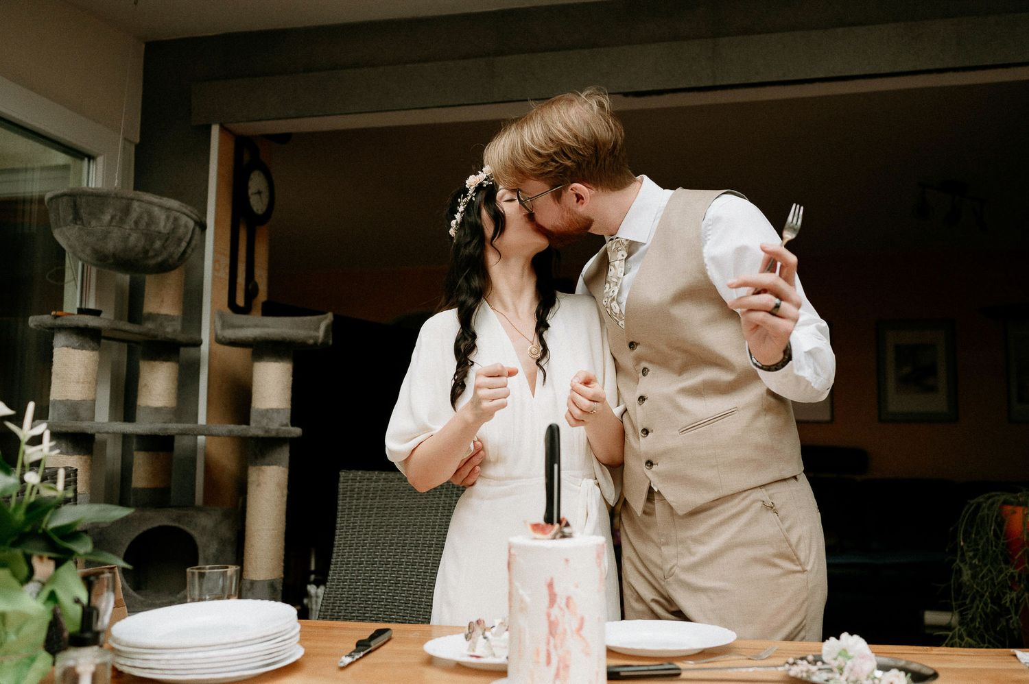 Wedding celebration scene with couple and small decorated cake on wooden table.