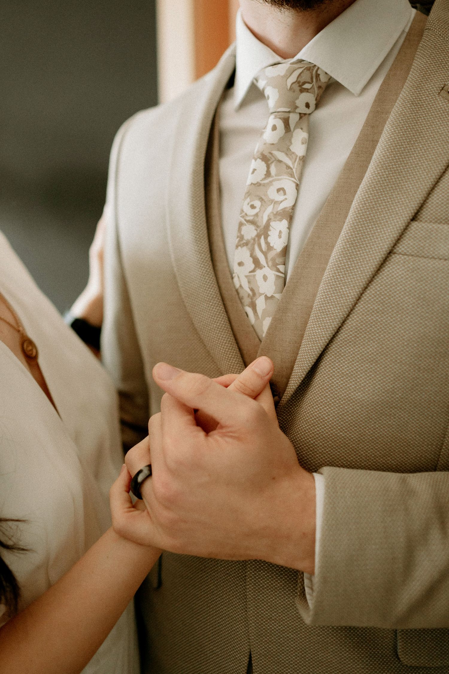 Close-up details of a beige suit with floral patterned tie.