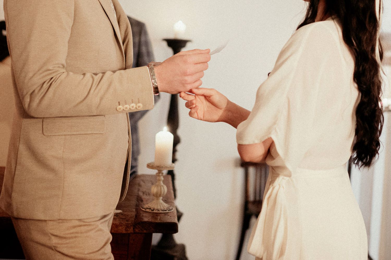 Exchange of rings during intimate ceremony in vintage indoor setting.