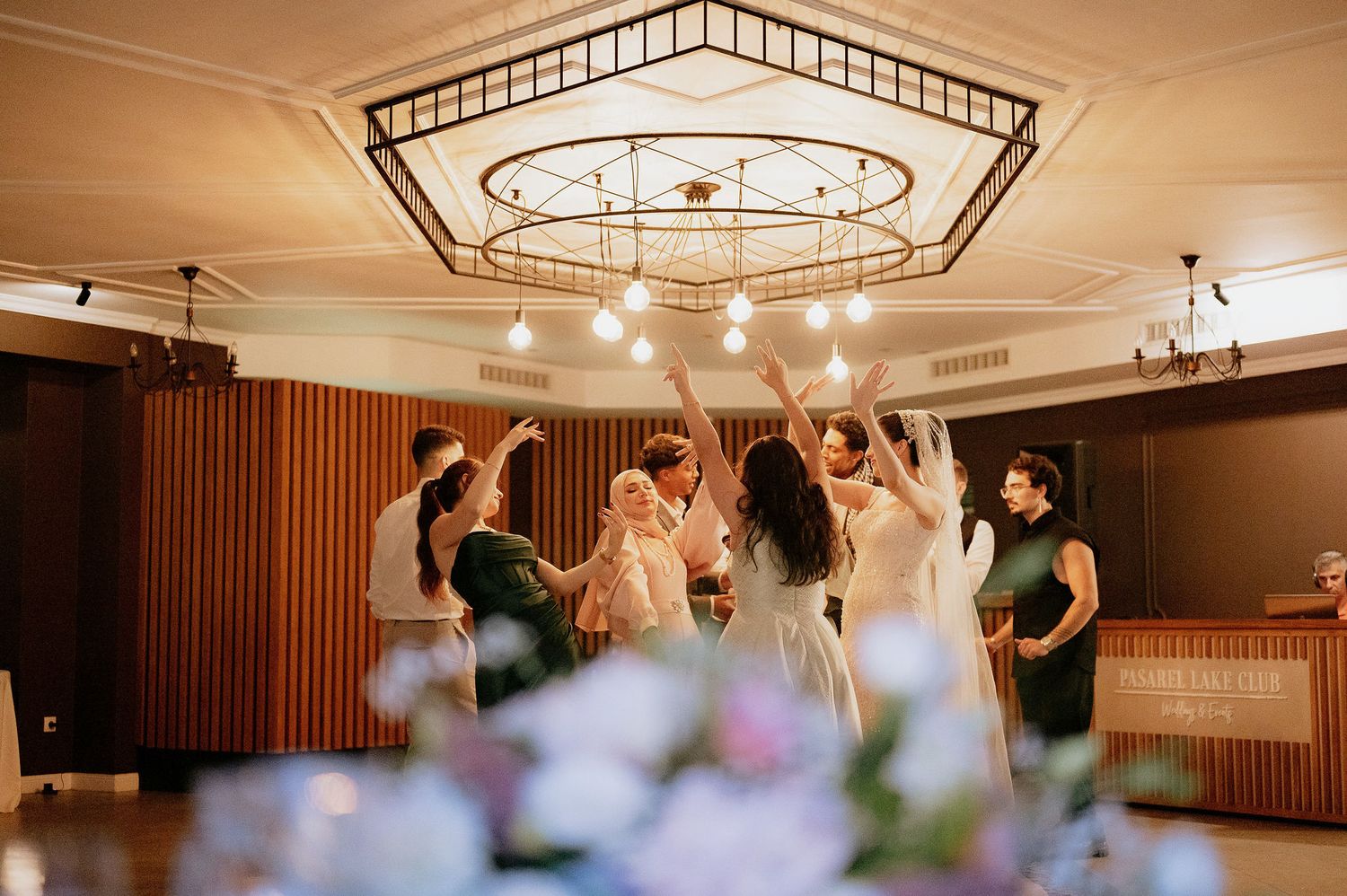 Reception venue interior features geometric ceiling patterns and modern string lighting.