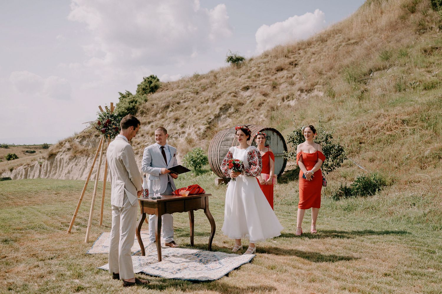 Wedding party gathered on a grassy hillside for an outdoor ceremony celebration.