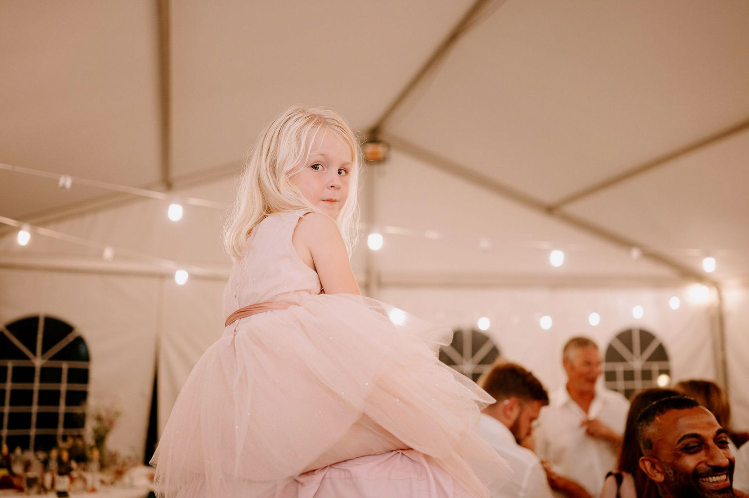 Joyful celebration on a wedding dance floor with guests dancing under warm lighting.