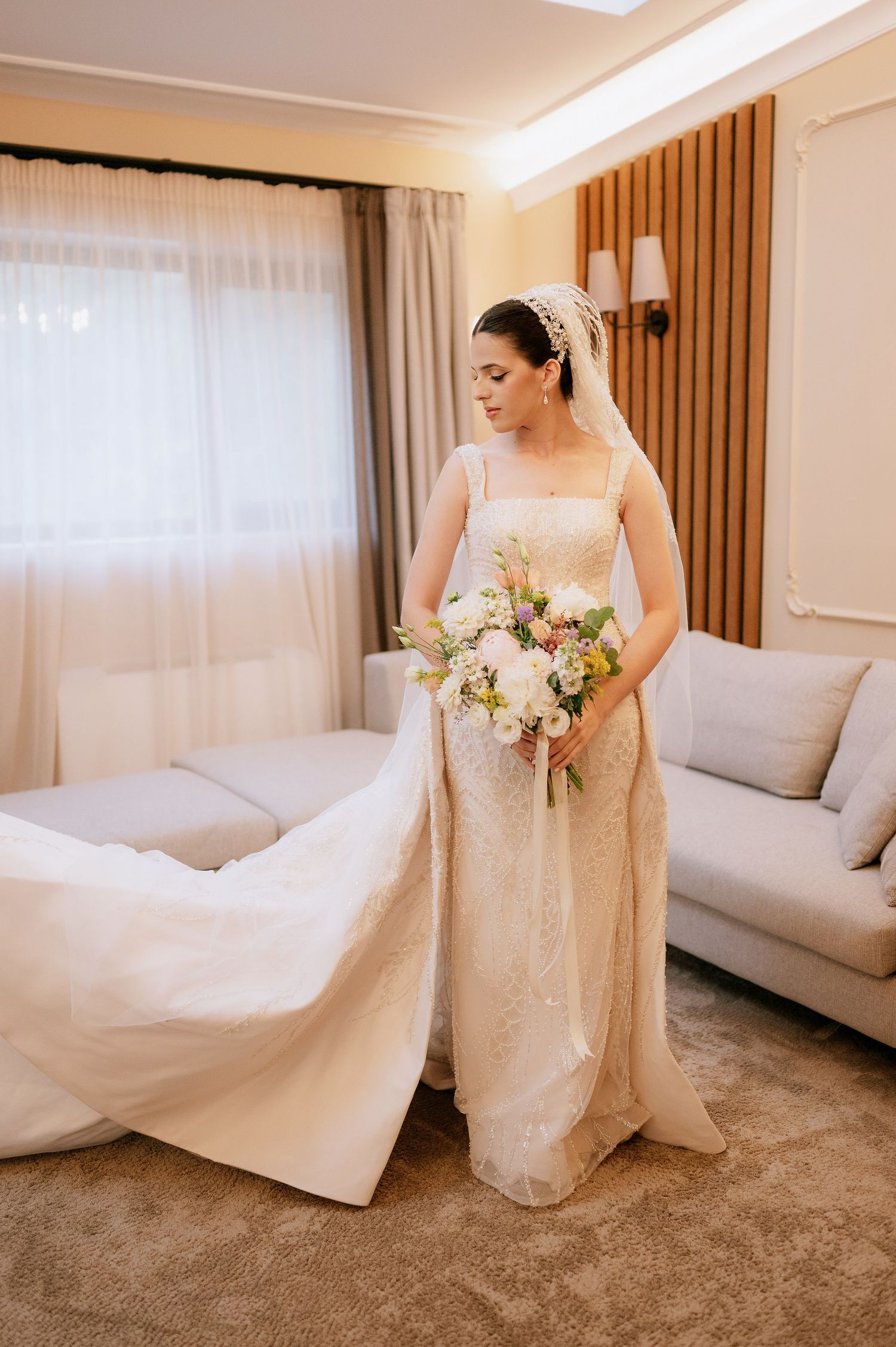 Classic bridal portrait featuring a fitted lace gown with cathedral train and soft floral bouquet.