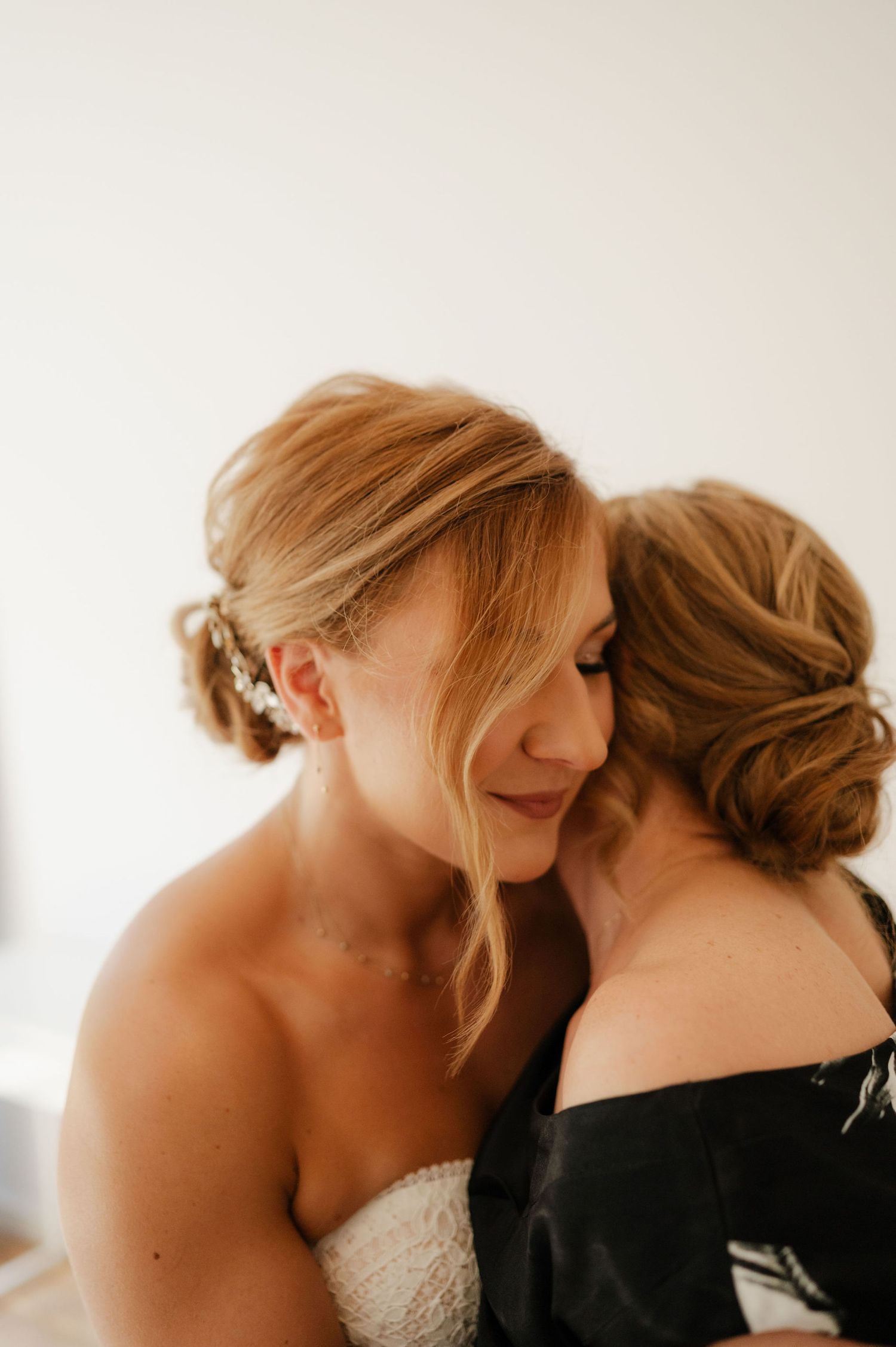 Two figures share an intimate moment against a bright white background.
