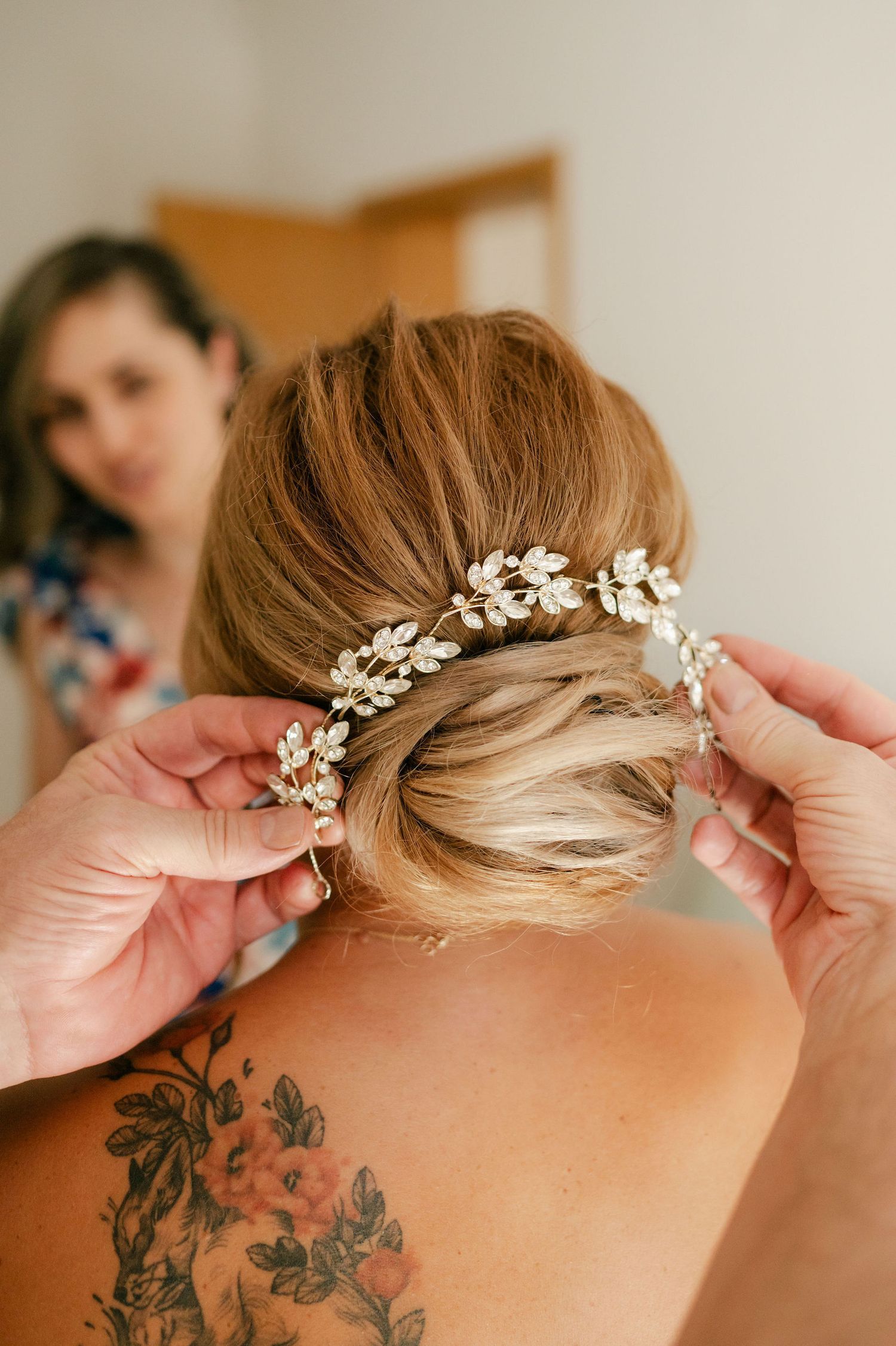 A delicate floral hair accessory is placed in a bridal updo hairstyle.
