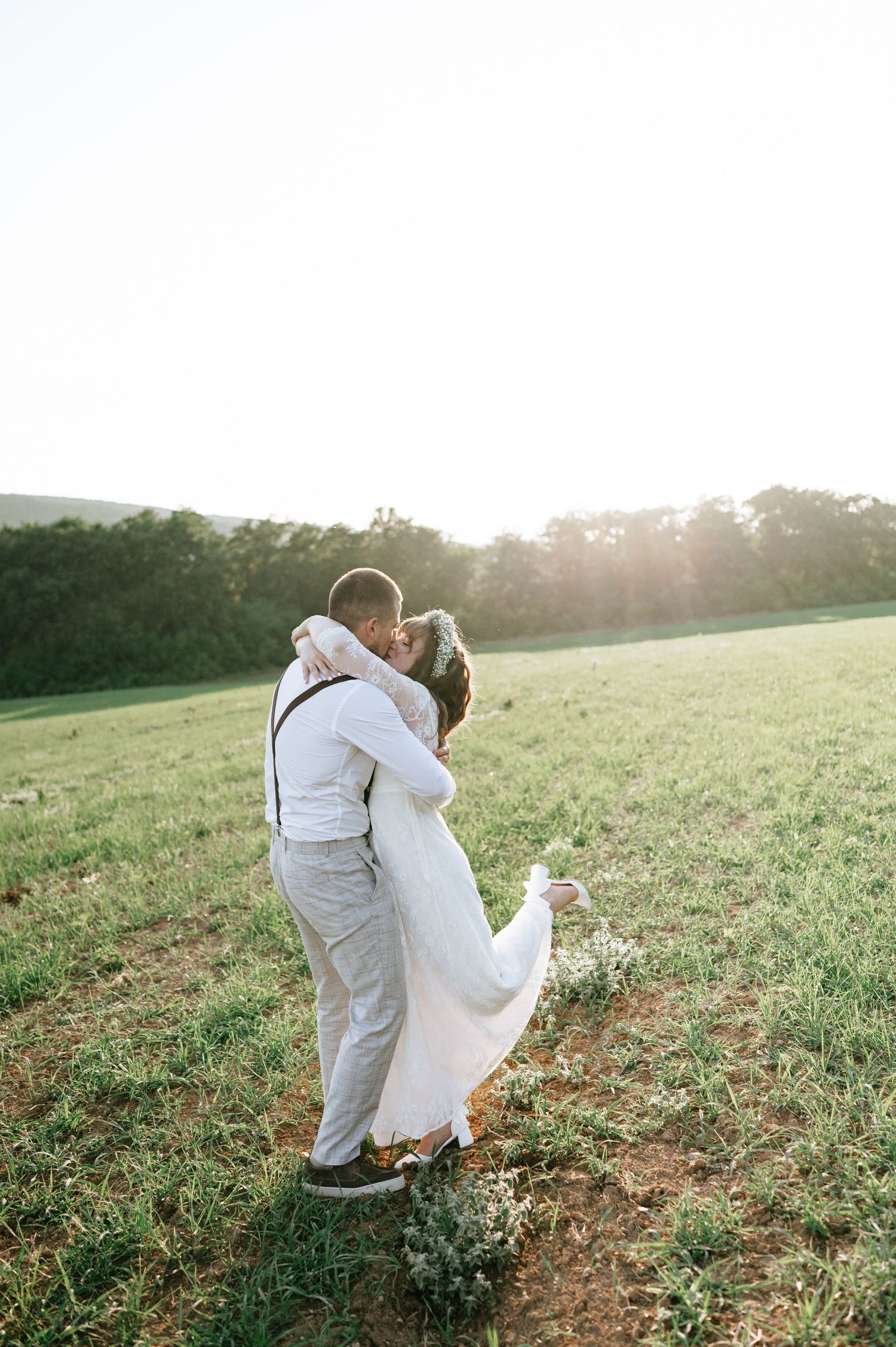 Romantic wedding couple embraces in a golden sunset field.