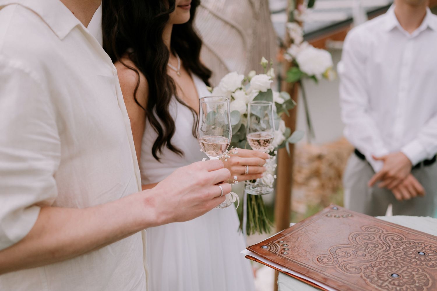 Elegant table setting with champagne glasses and white floral arrangements outdoors.