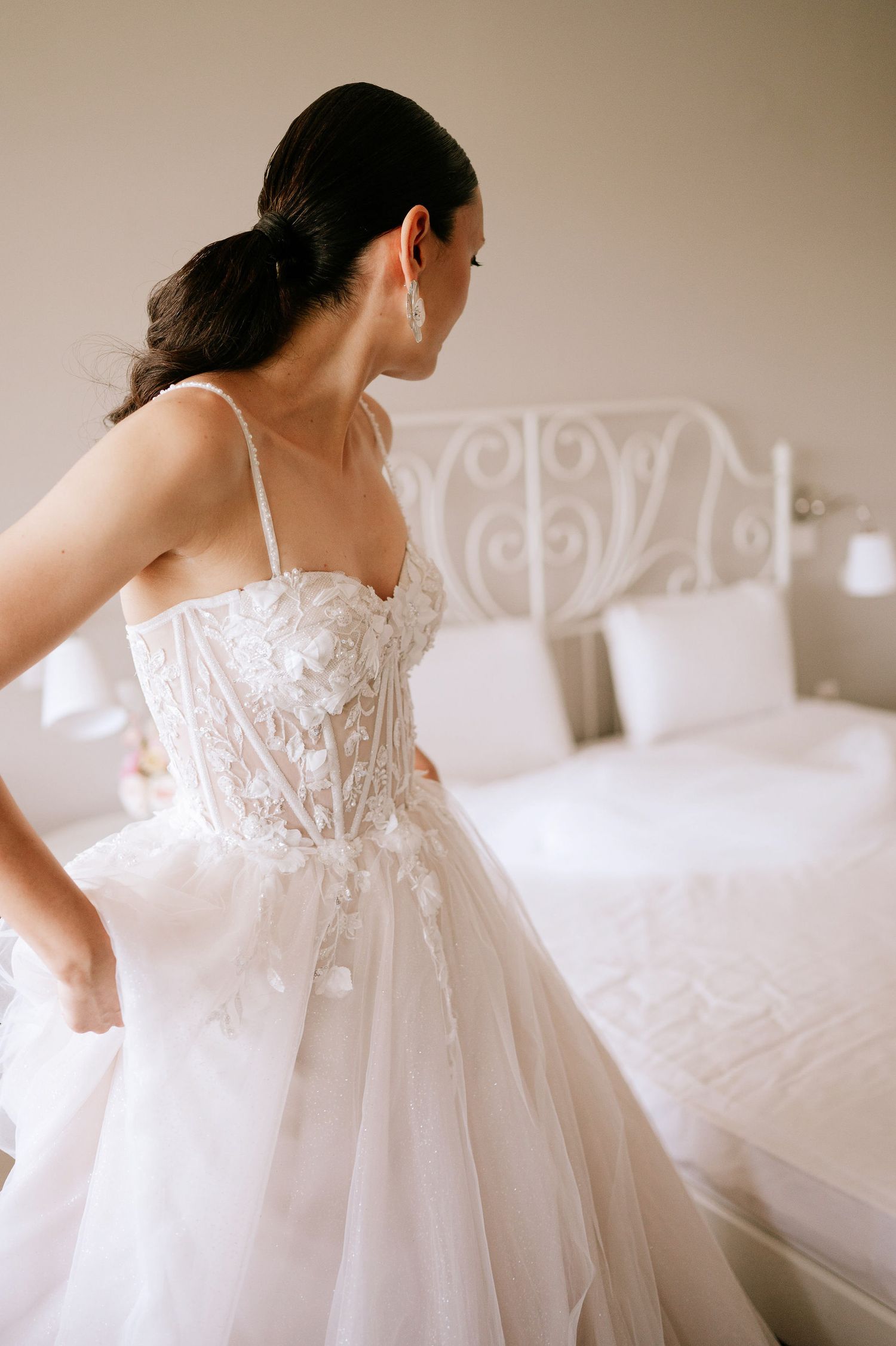 Side view of wedding dress showing detailed lace bodice and flowing tulle skirt in natural light.