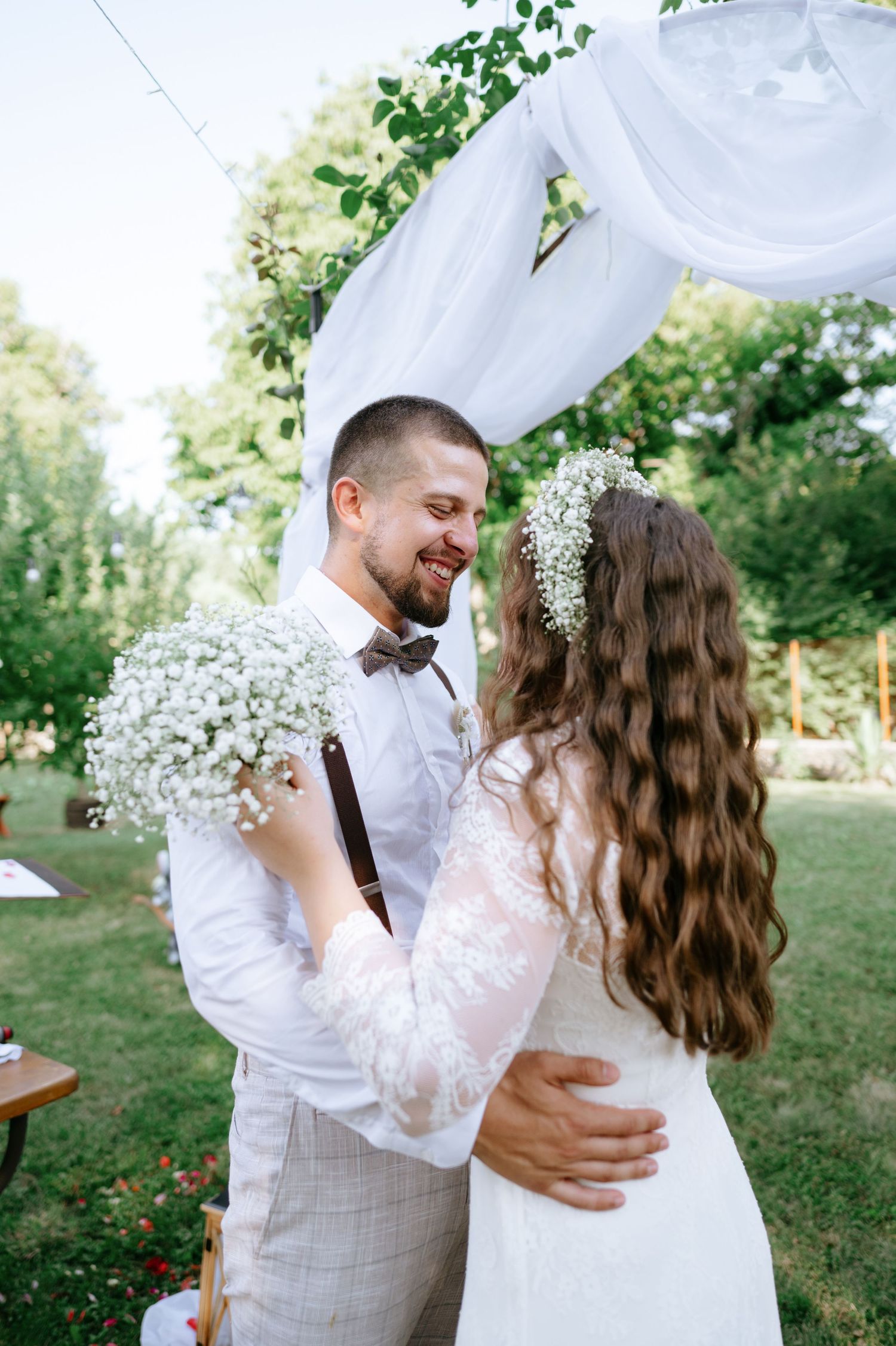 A tender moment captured during an outdoor wedding with baby's breath bouquets and a flowing white dress.