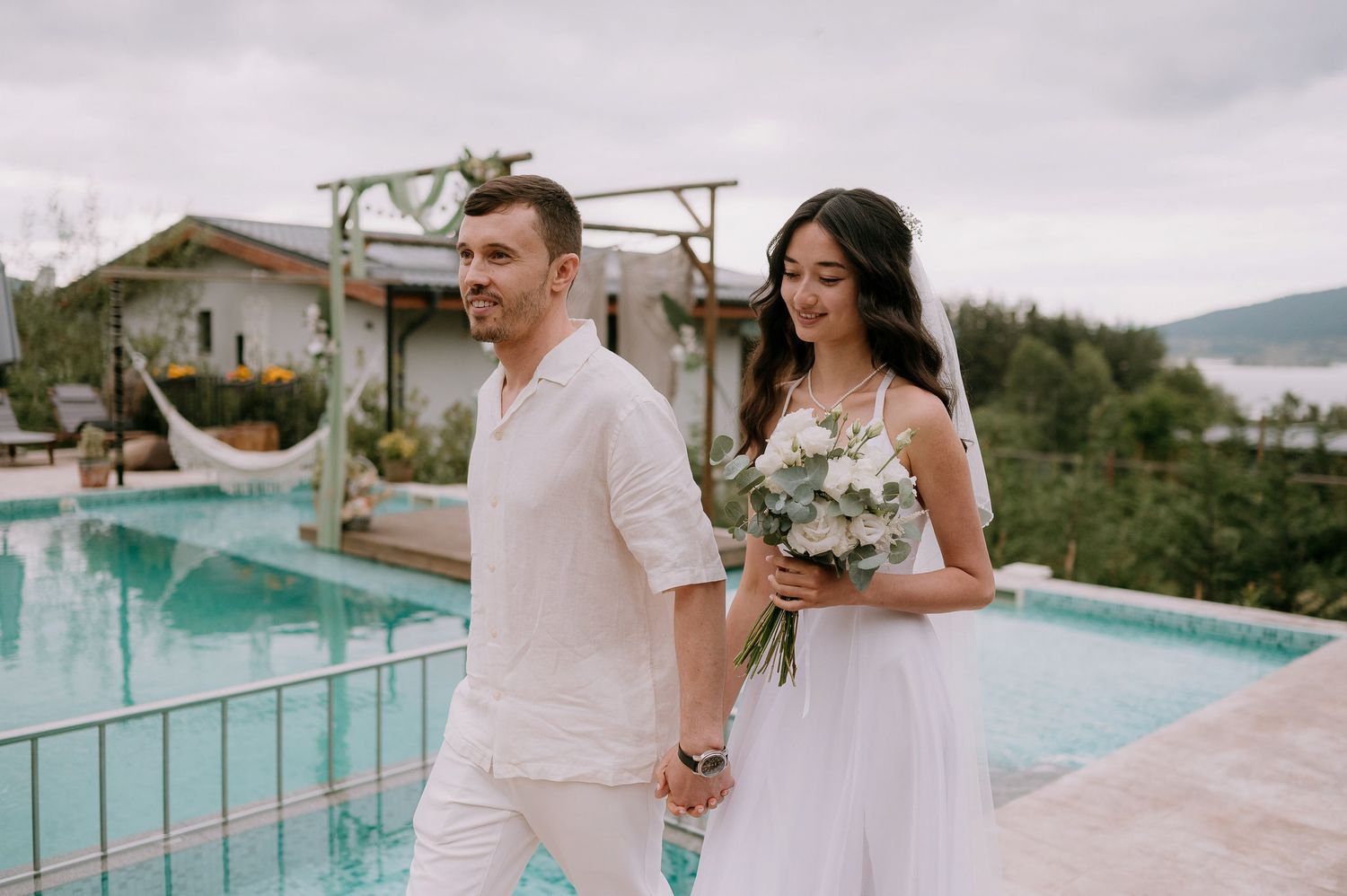 Wedding venue featuring a decorated wooden arch and infinity pool with mountain vistas.