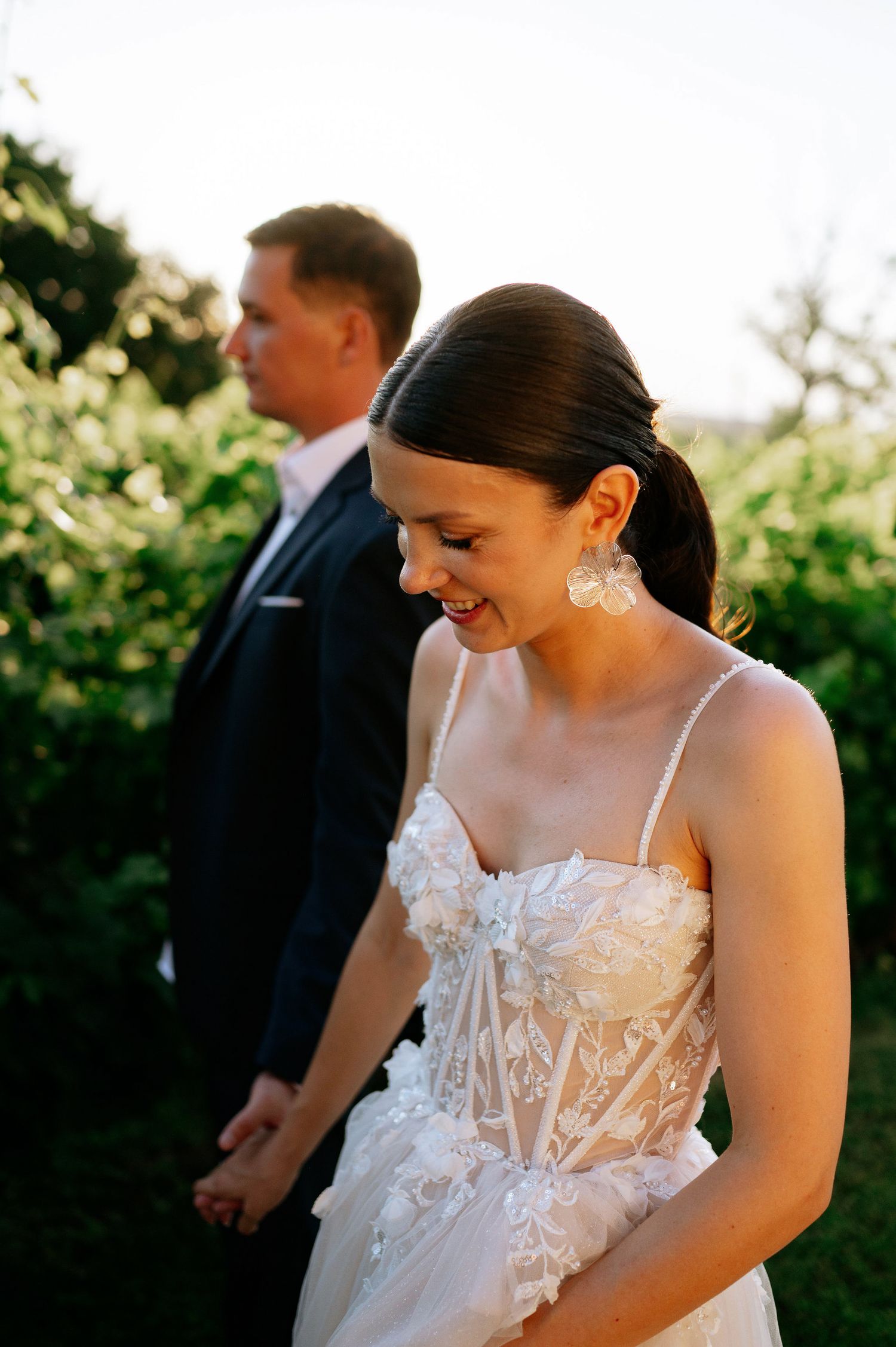 Candid wedding moment captured in golden hour light with lush garden backdrop.