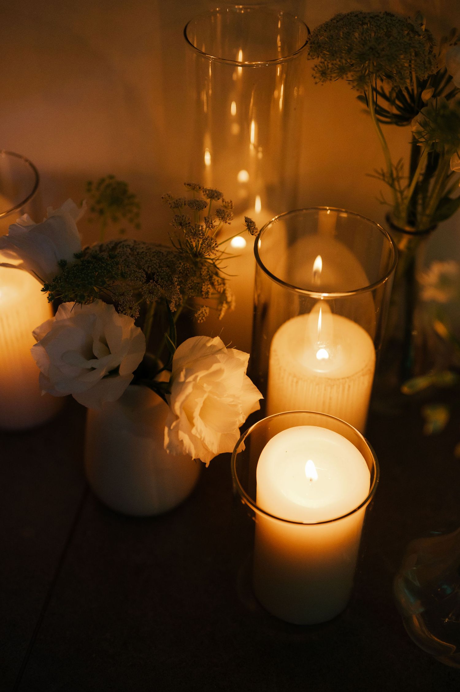 Glowing candles and white roses create an intimate wedding reception atmosphere.