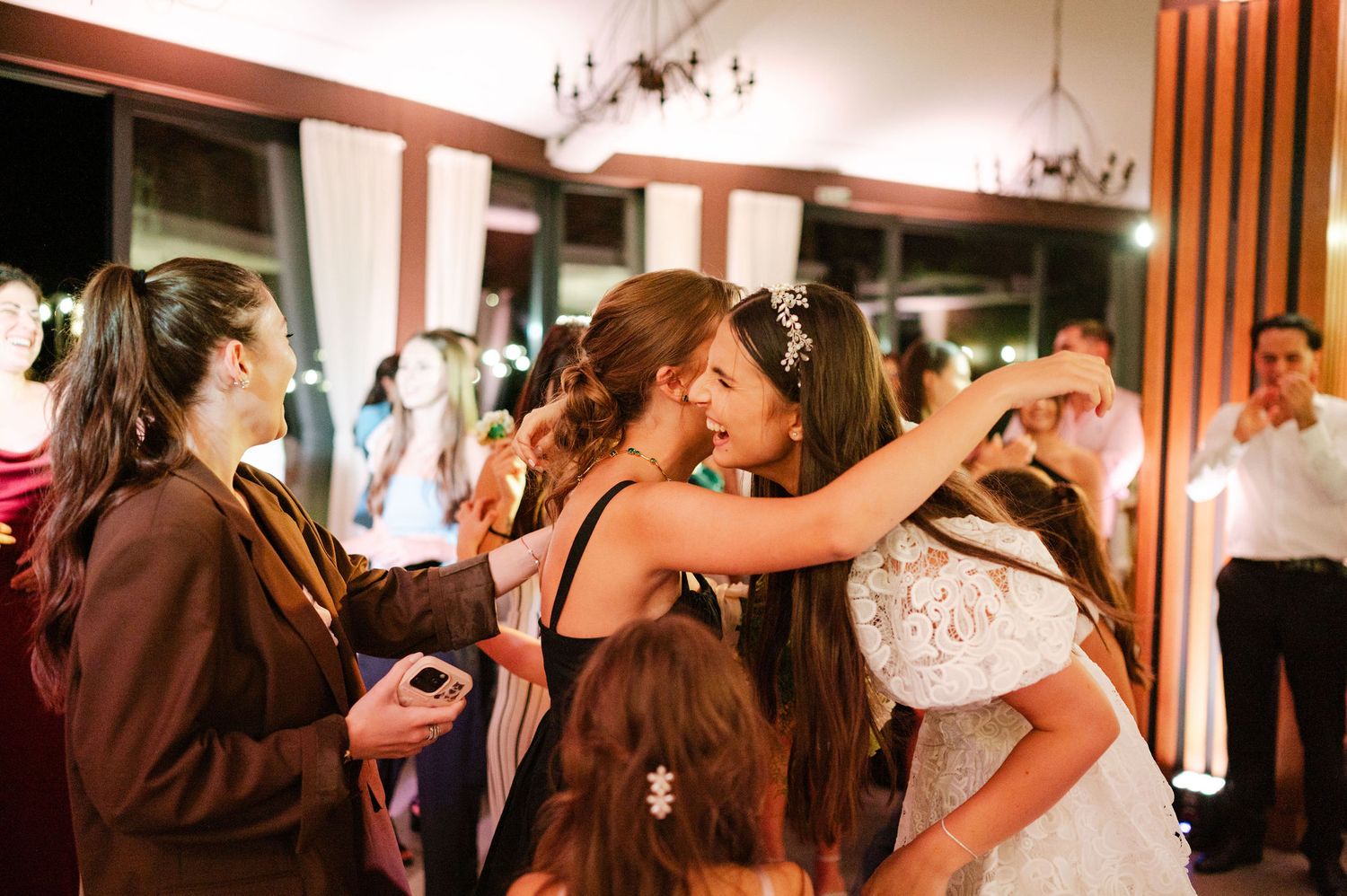 Guests embrace and celebrate during an emotional moment at an indoor wedding reception.
