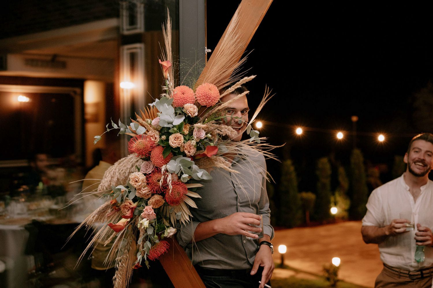 Romantic evening wedding reception with warm lighting and floral decorations on rustic wooden tables.