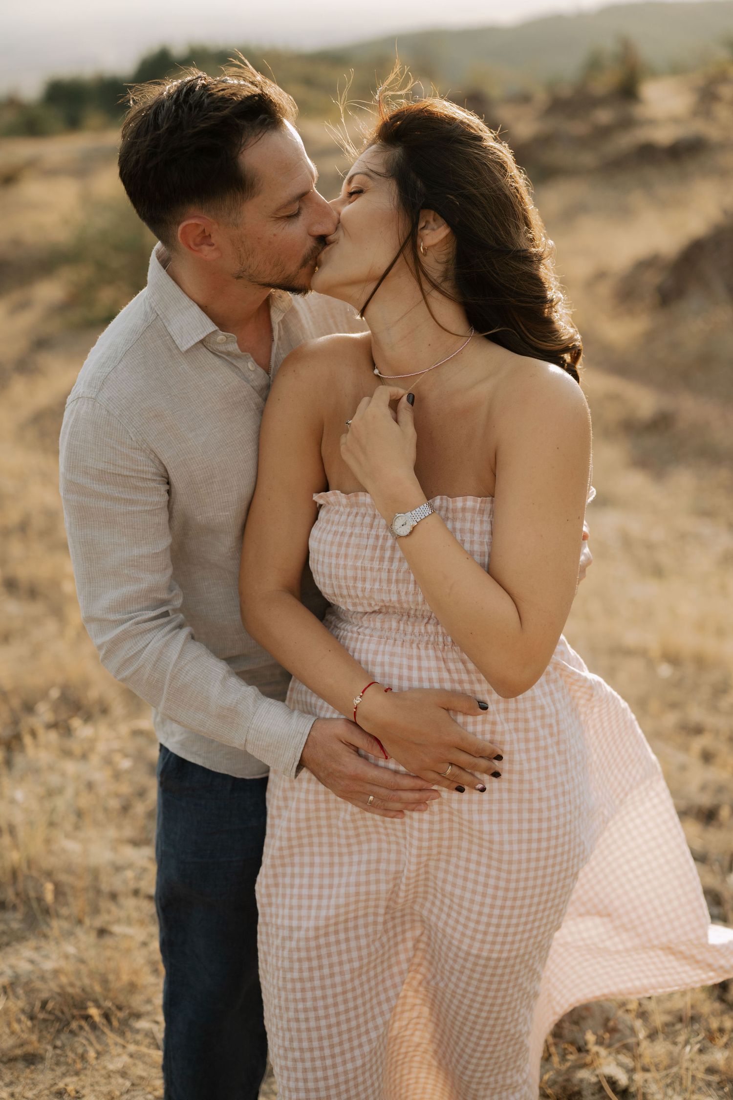 Intimate couple shares tender moments together in a scenic outdoor setting during sunset.