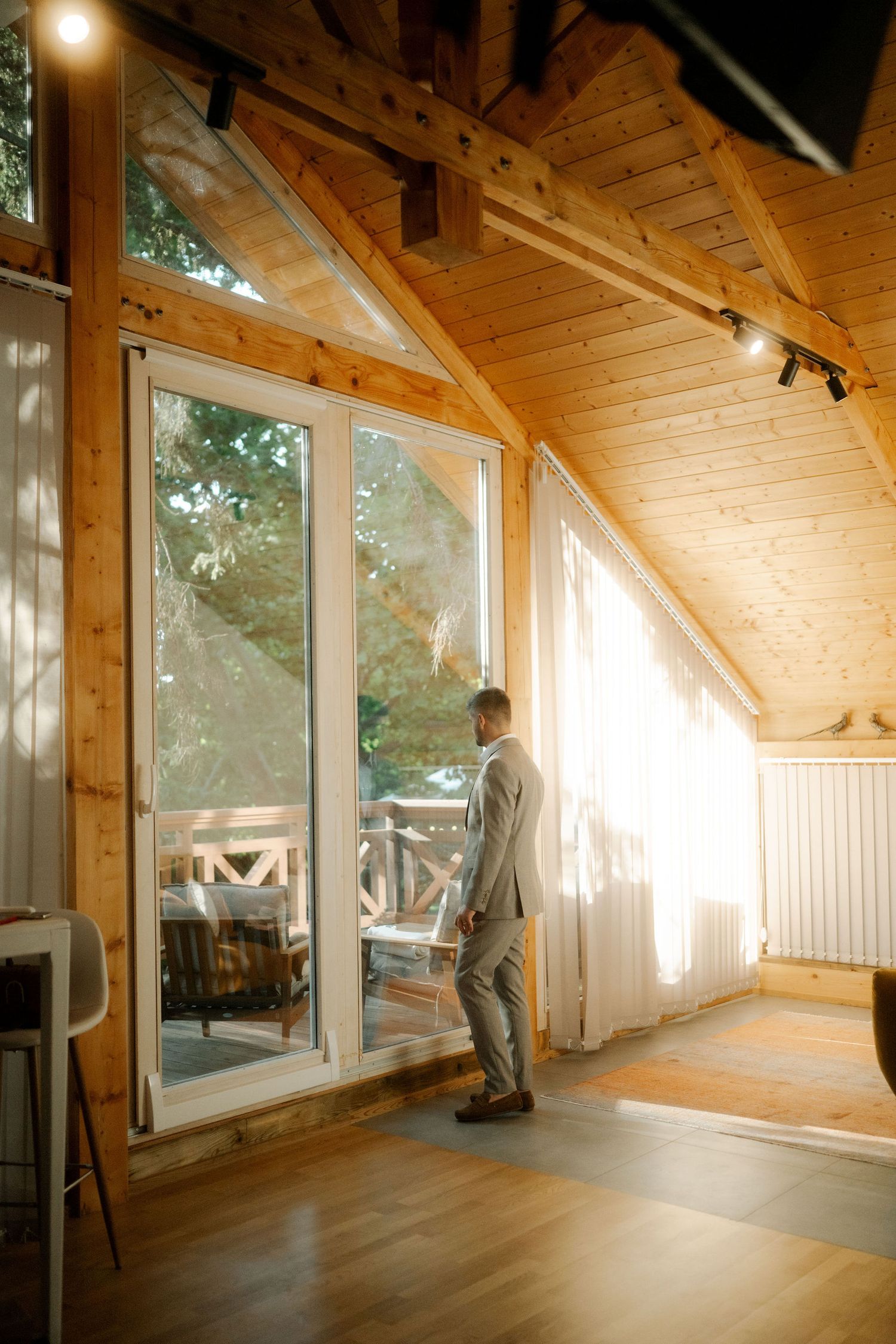 Sunlit wooden interior space with large windows and vaulted ceiling showing progression of natural light throughout the day.