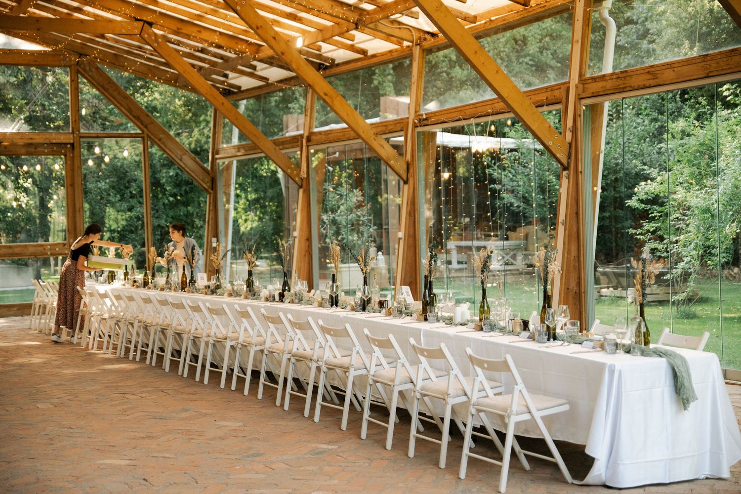 Rustic wooden pavilion with exposed beams and rows of white chairs set up for an outdoor wedding ceremony.